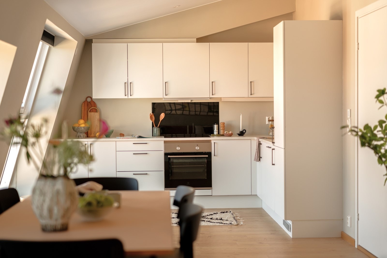 Kjøkkeninnredningen utgjør et stilrent møbel i seg selv og består av innredning med slette, hvite fronter og sorte grep. Galleribilde