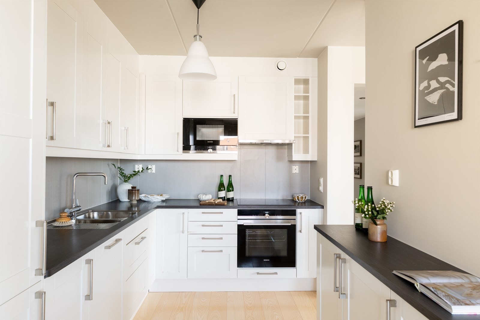 Moderne innredning bestående av profilerte fronter og benkeplate av laminat med belysning over benkeplaten og nedfelt vask- og skyllekum. Galleribilde