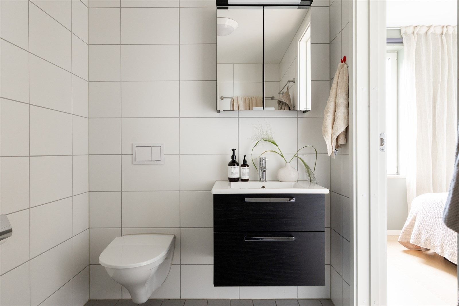 Badet er innredet med vegghengt klosett, servant nedfelt i innredning, speilskap m/lys og dusjhjørne med svingbare glassdører. Galleribilde