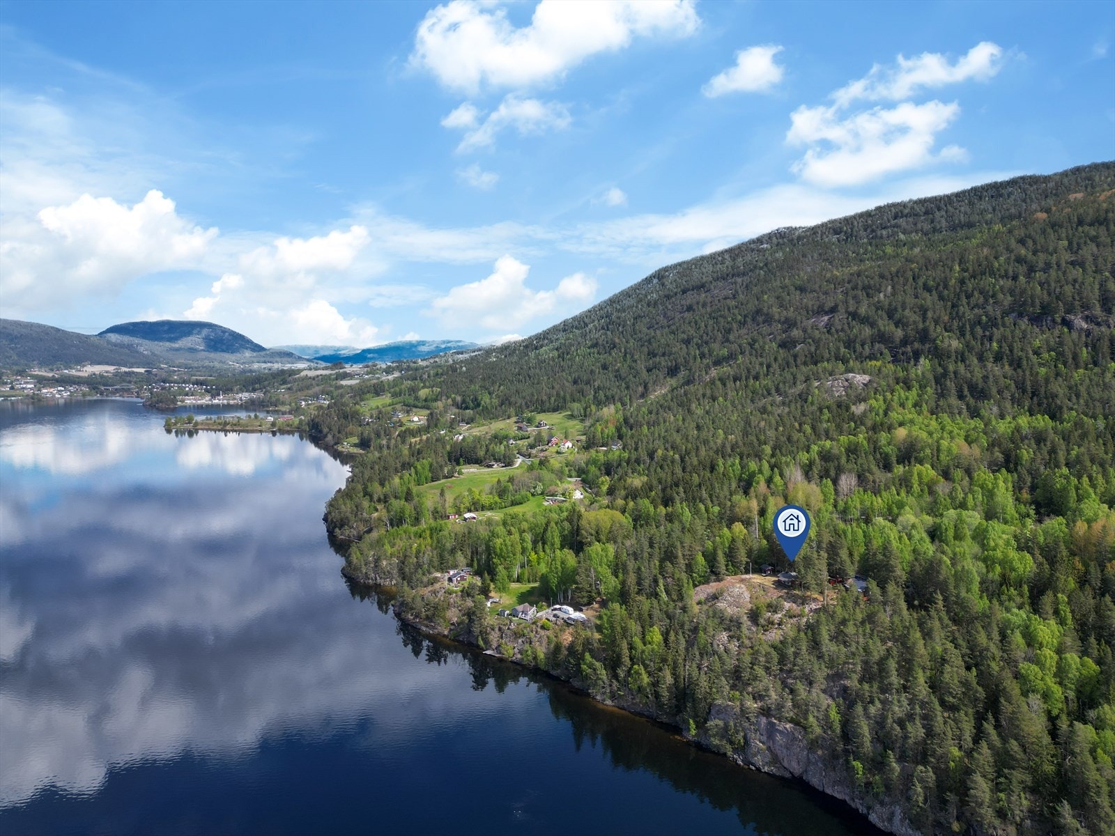 Hytta ligger fint til i terrenget med utsikt over vannet. Galleribilde