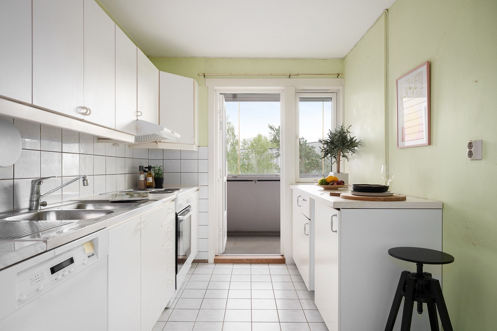Eldre kjøkkeninnredning med laminat benkeplate, fliser over benk, kullfilter vifte og benkebeslag med 2 kummer. Galleribilde