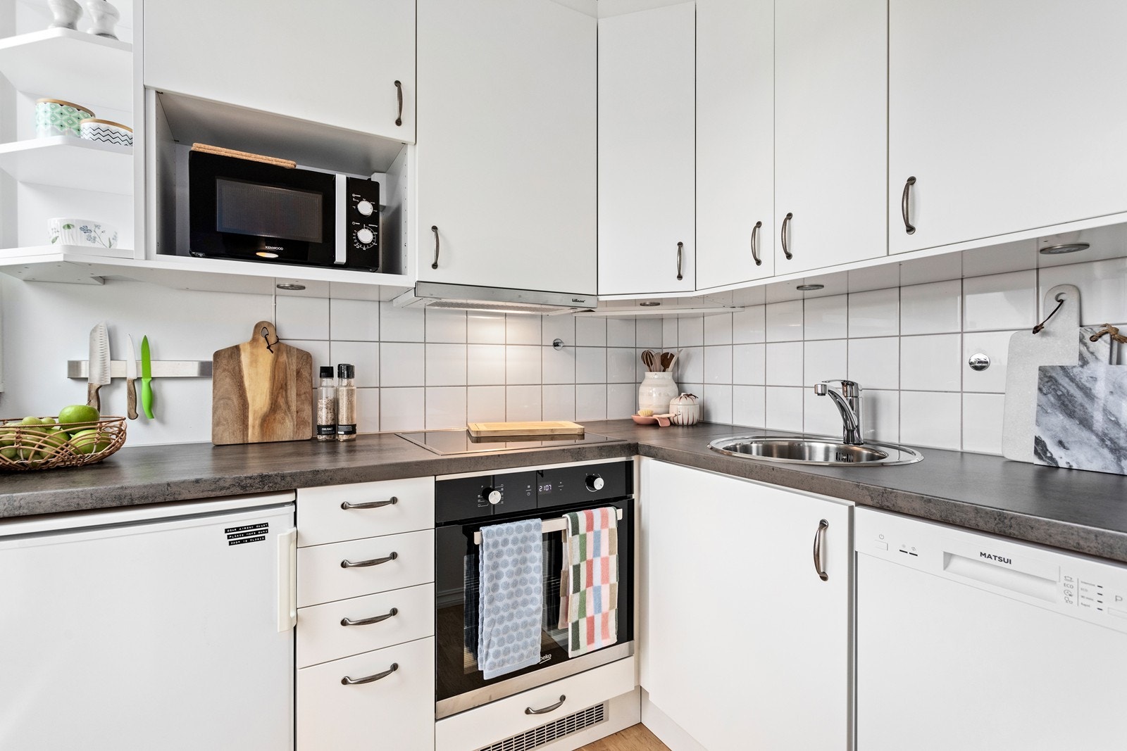 Kjøkkenet er plasseffektiv og innreiinga er tidlaus med kvite, slette frontar. Benkeplate i laminat og fliser som veggbeskyttelse mellom over- og underskap. Galleribilde
