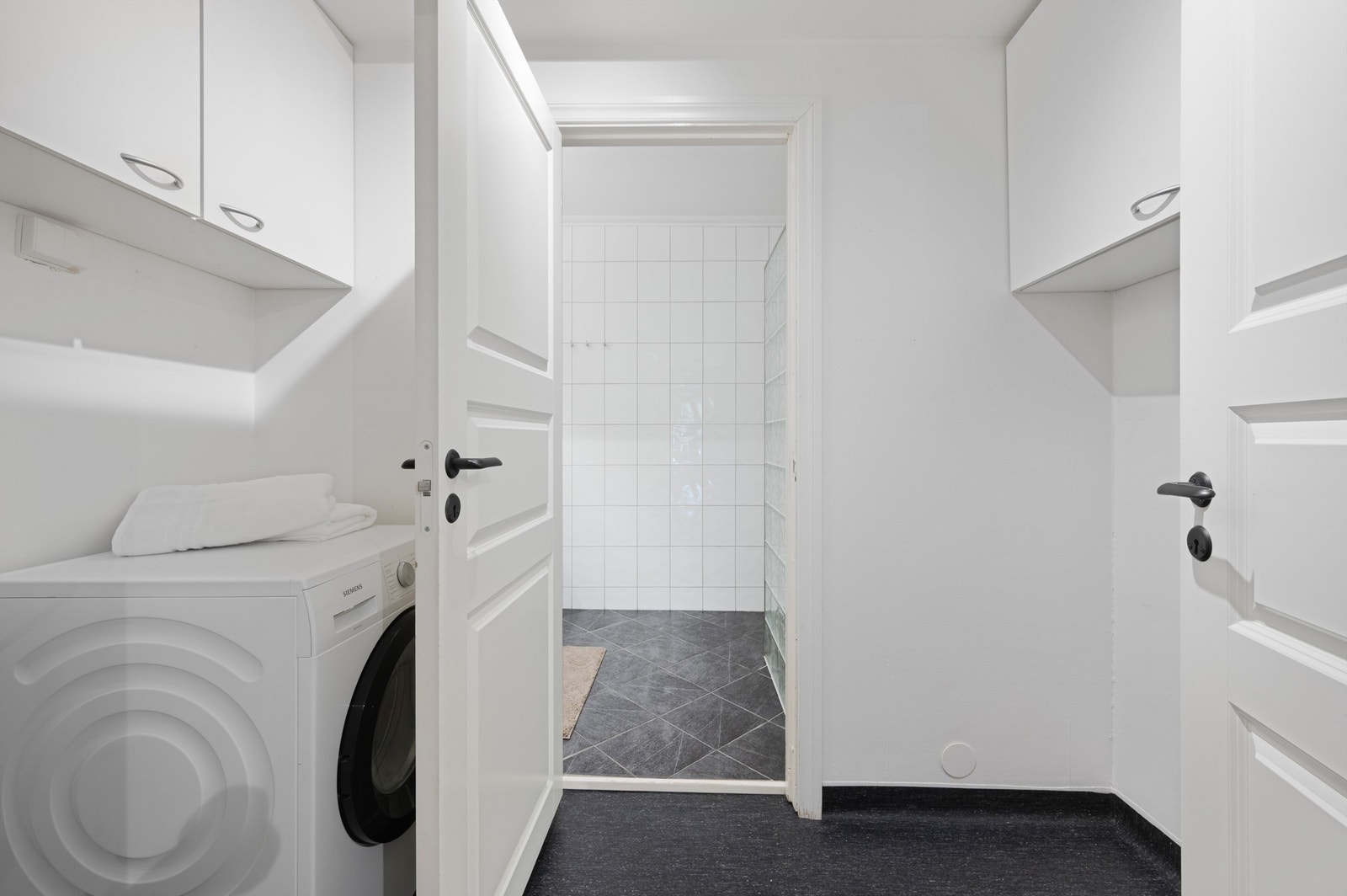 Leiligheten har eget vaskerom med god plass til vaskemaskin og er innredet med veggehengte skap for oppbevaring Galleribilde