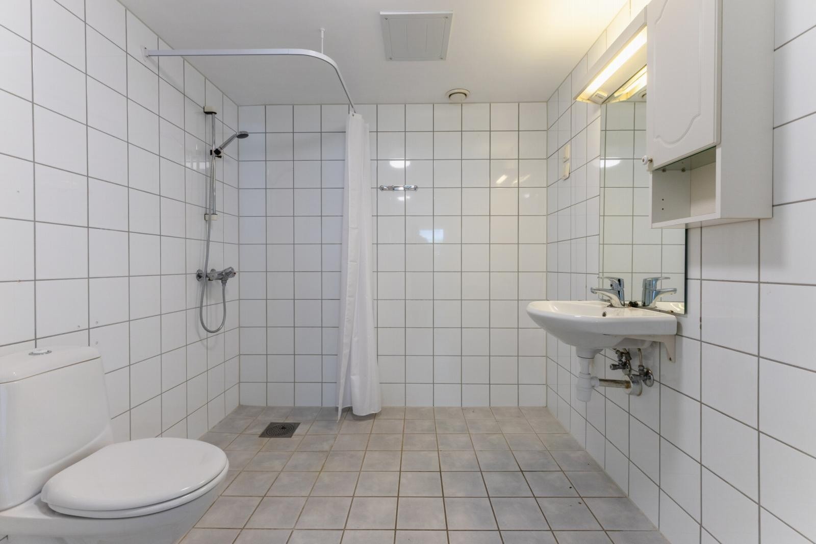Dusjbad/wc, med opplegg for vaskemaskin. Håndvask med speil over og 1 skap. Galleribilde