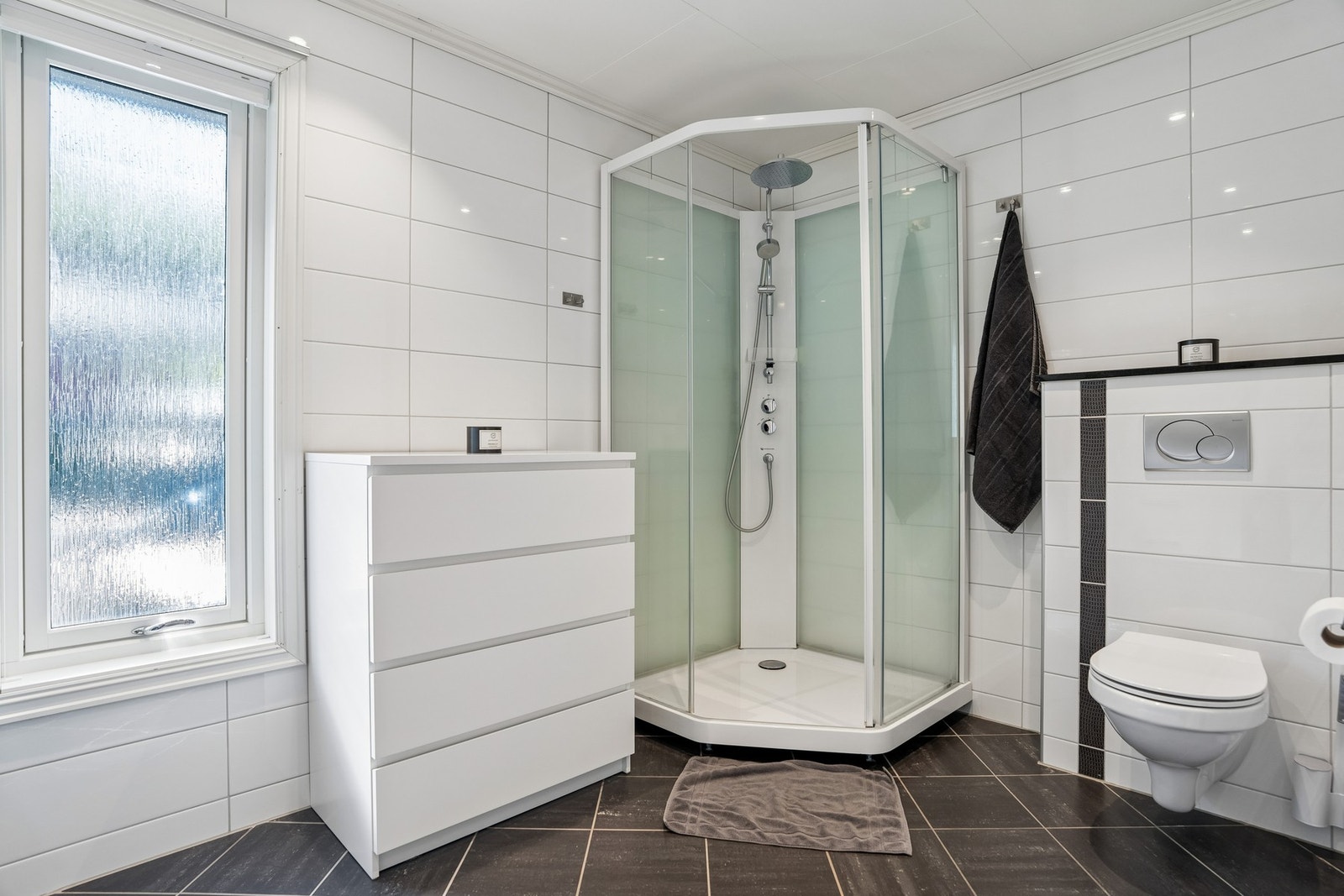 Badet har en praktisk utforming med god skapplass og romslig dusjløsning. Galleribilde