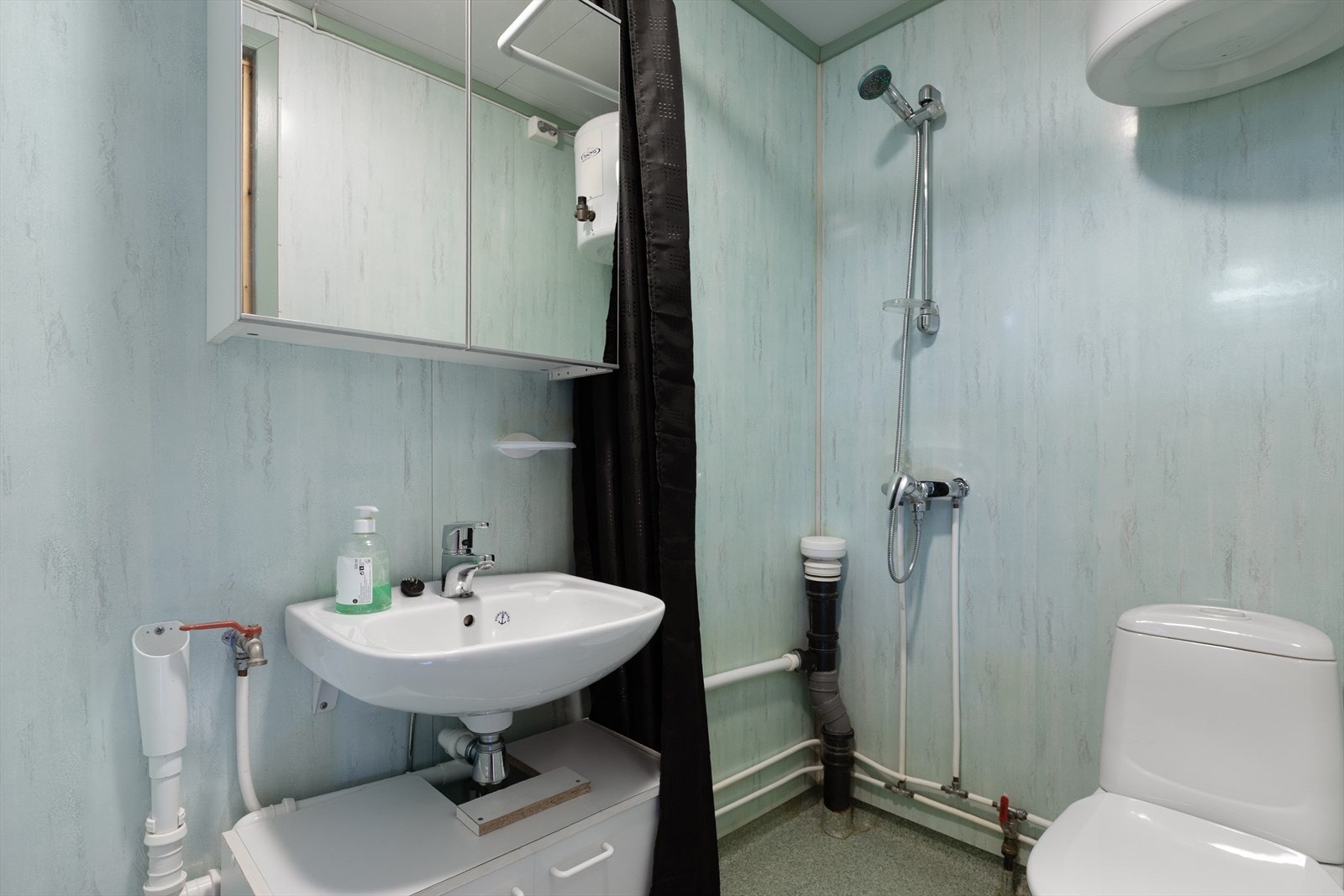Badet i den andre boligen har vinylbelegg på gulv, våtromsplater på vegg og opplegg for vaskemaskin. Galleribilde