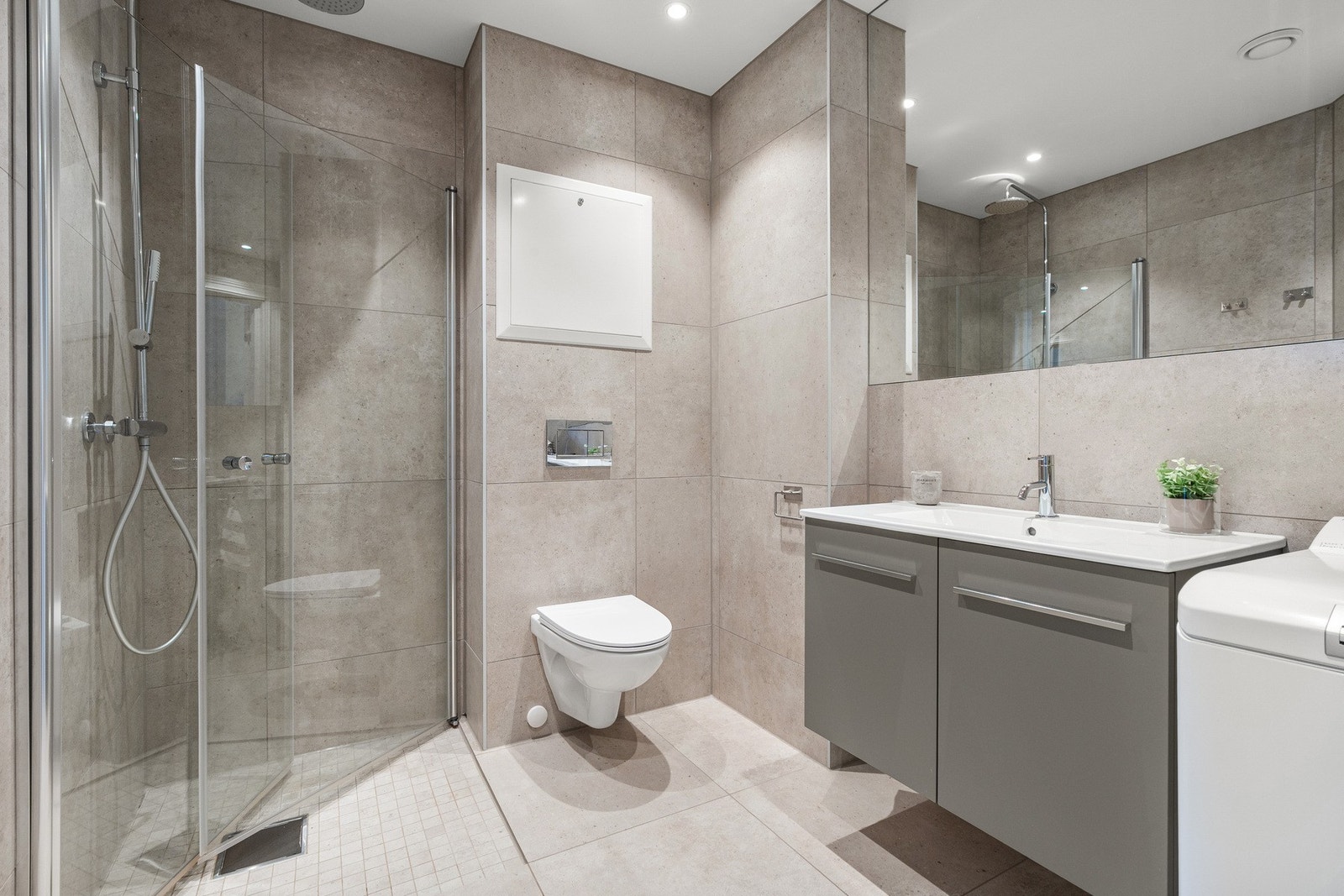 Badet ble etablert i 2024 og fremstår moderne med flislagte overflater og innfelte downlights i himling. Gulvet er belagt med 60x60-fliser, mens dusjsonen har nedsenket løsning med mosaikkfliser. Galleribilde