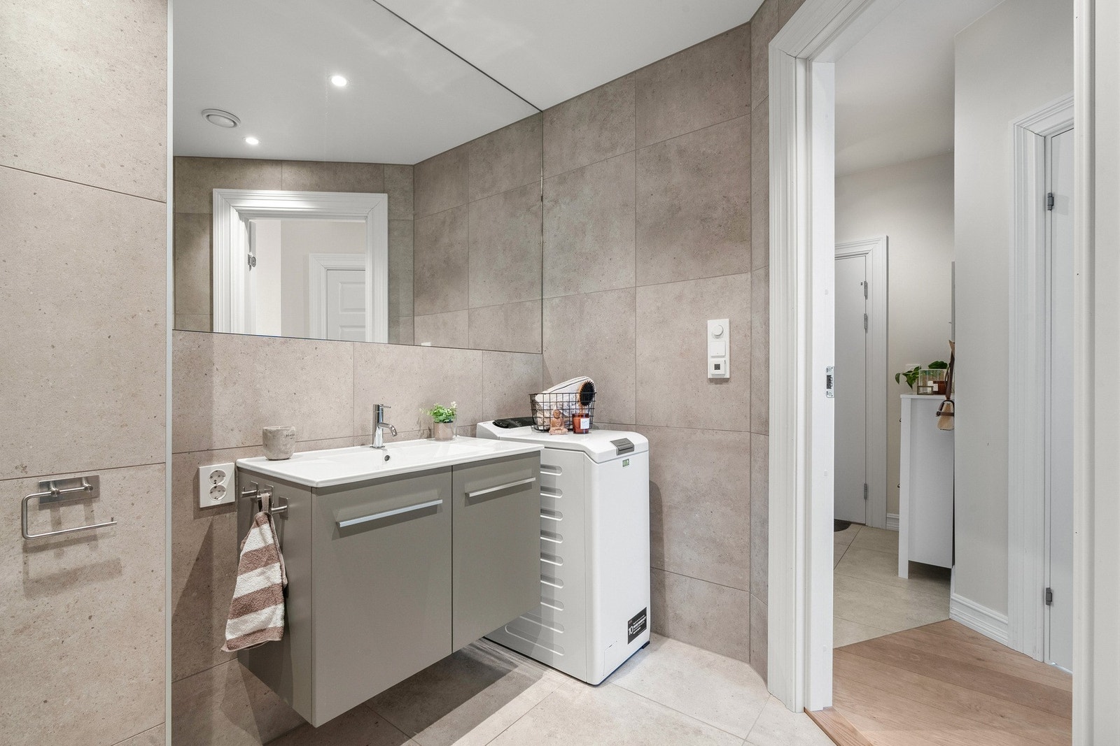 Badet er innredet med vegghengt toalett, servant med tilhørende innredning fra Brødrene Dahl og dusjhjørne med innsvingbare glassdører. Armaturer og dusjbatteri er fra Tapwell i rustfritt stål. Det er gulvvarme, mekanisk avtrekk og opplegg for vaskemaskin Galleribilde