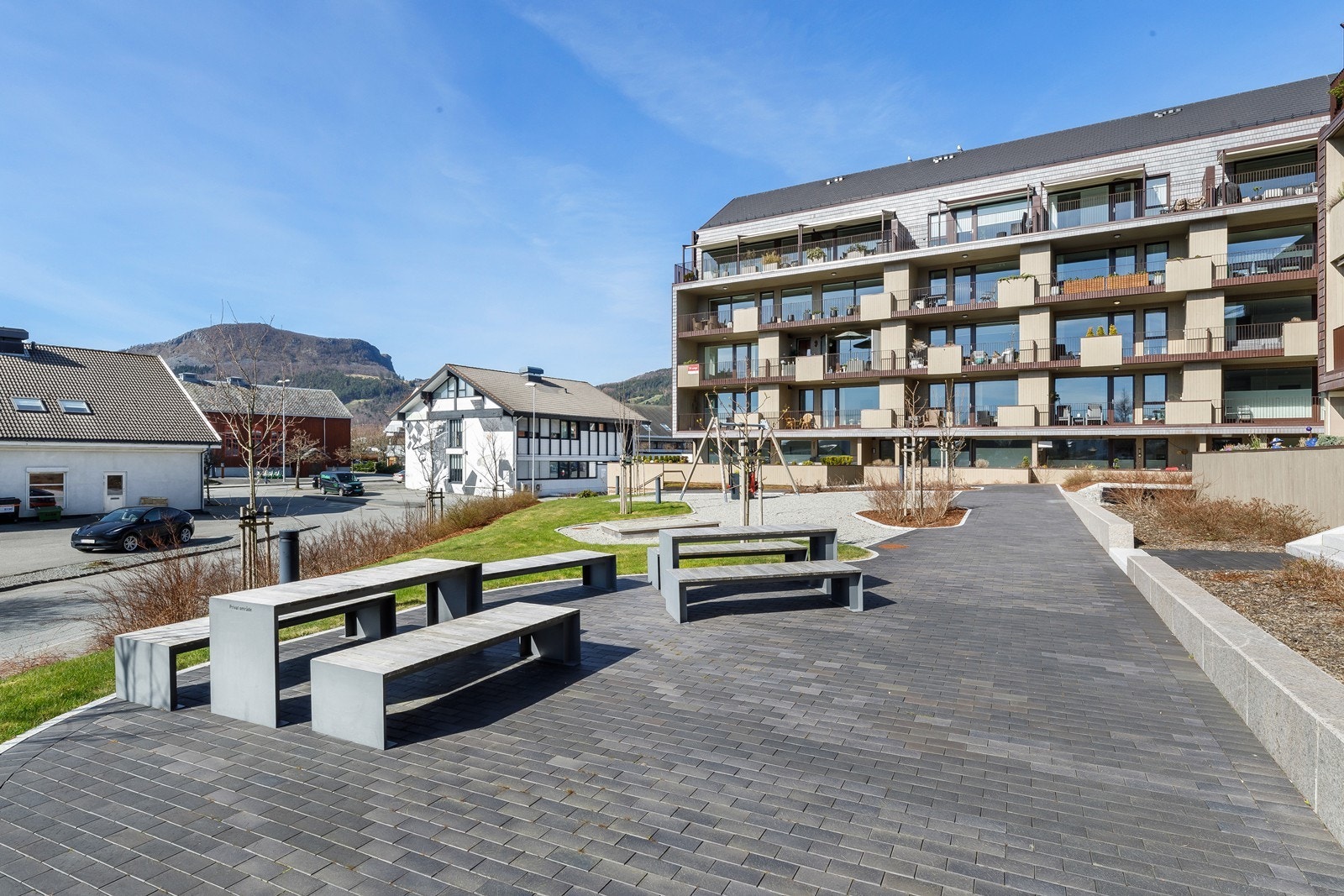 Flott opparbeidet fellesområde med sittebenker, lekeapparater for barn, gressplen og beplantning. Galleribilde