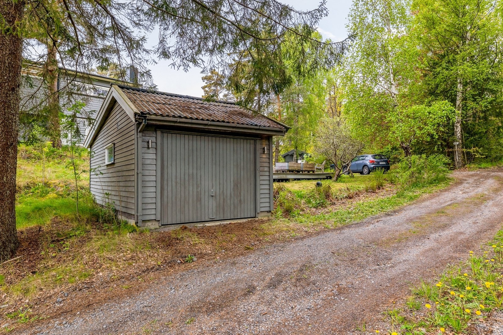 Garasje fra 1979 med vippeport i tre og en praktisk bod på 7 m² i bakkant. Galleribilde