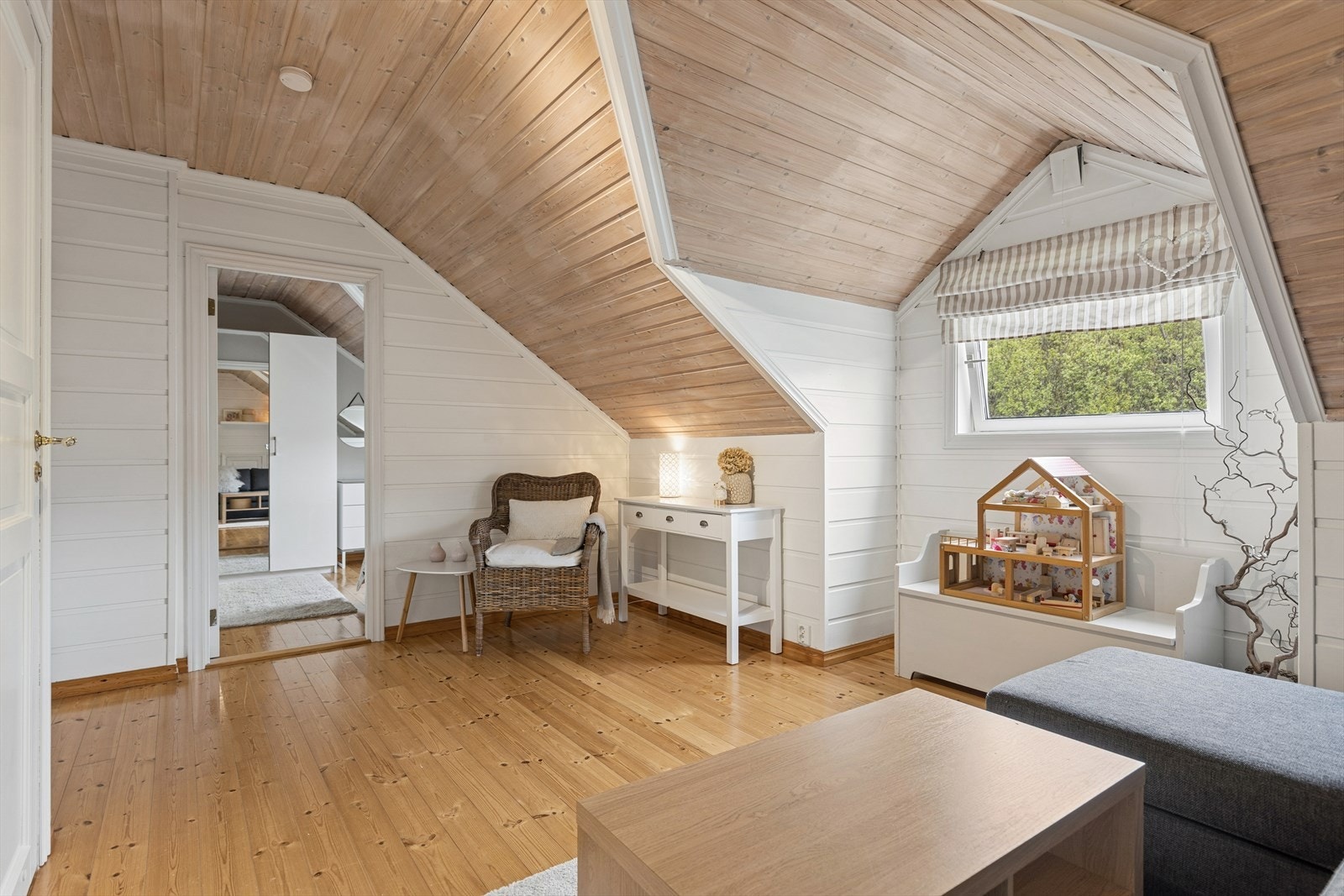 Loftstue med skråtak og synlige tretak som gir rommet særpreg. God gulvplass gir fleksible møbleringsmuligheter, og vinduet slipper inn naturlig lys. Galleribilde