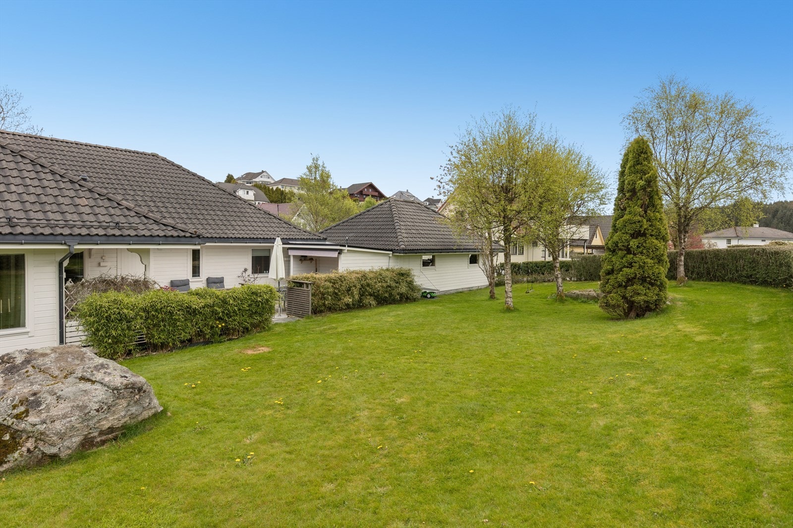 Stor og åpen hage med plen, beplantning og flere oppholdsarealer. Boligen ligger skjermet til med gode solforhold og fin avstand til omkringliggende bebyggelse. Galleribilde