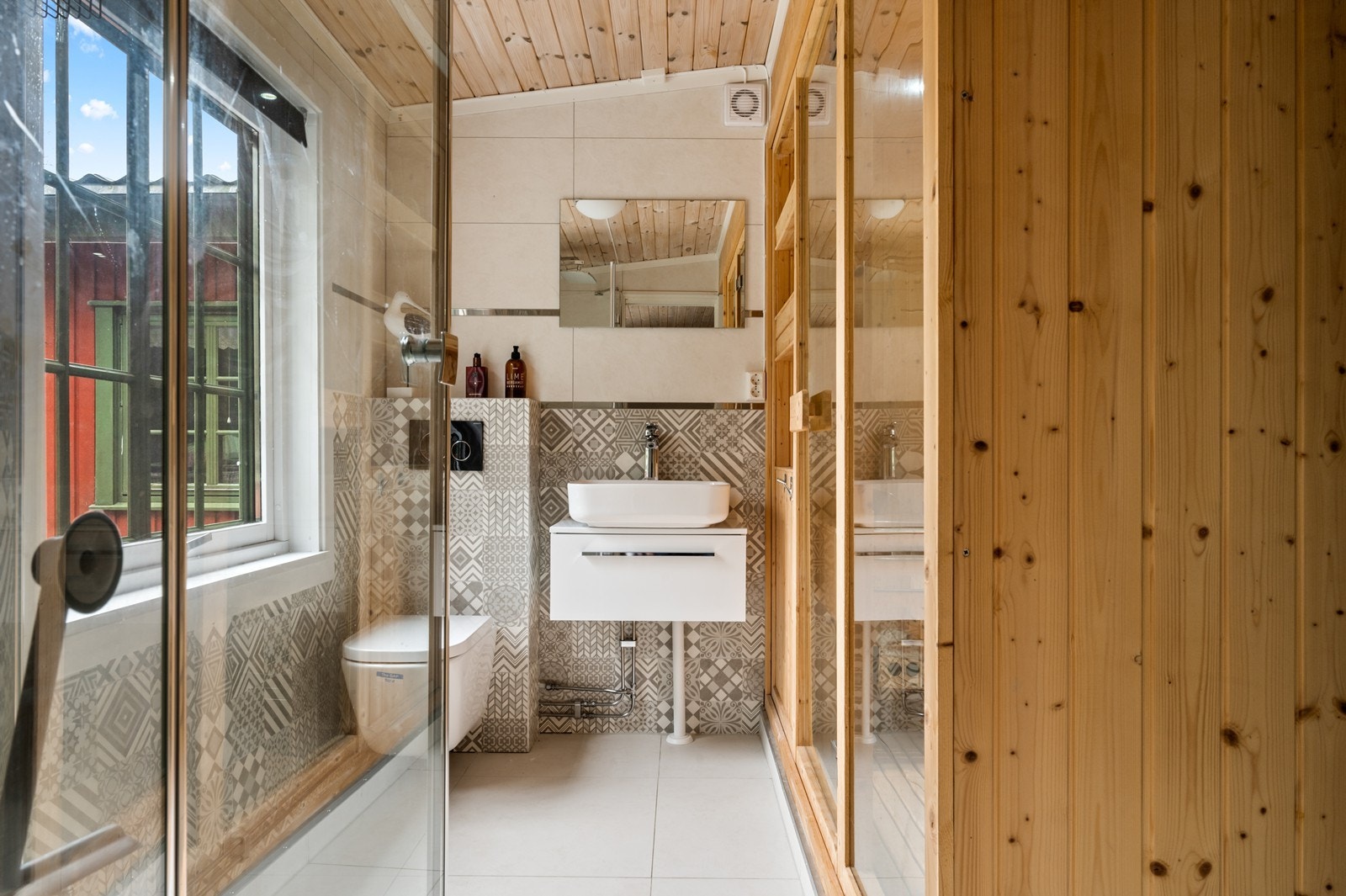 Badet i annekset har en moderne standard med delikate fliser og vegghengt toalett. Galleribilde