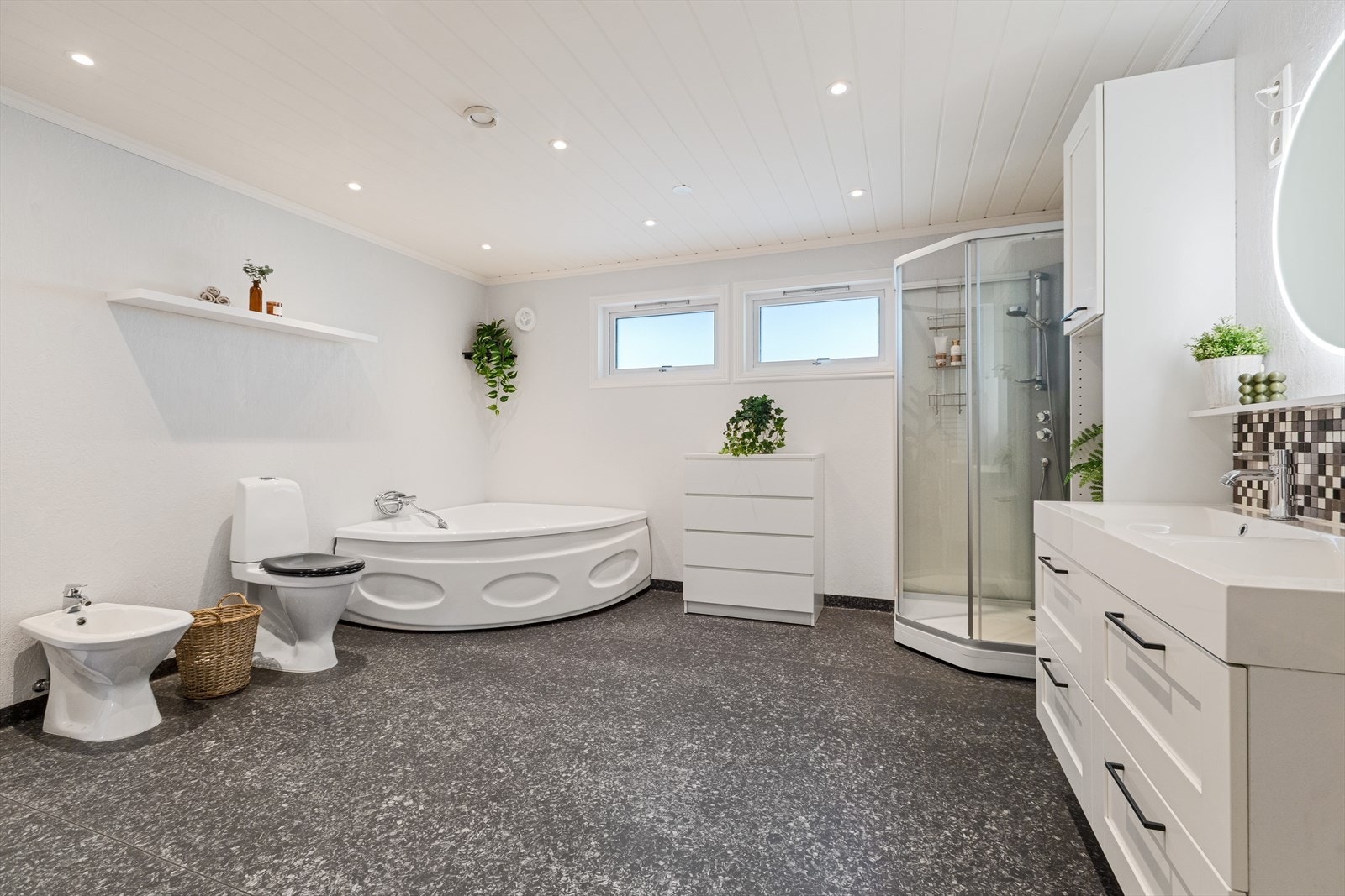 Badet har både badekar og dusjkabinett- toalett og bidè- og innholdsrik baderomsinnredning Galleribilde