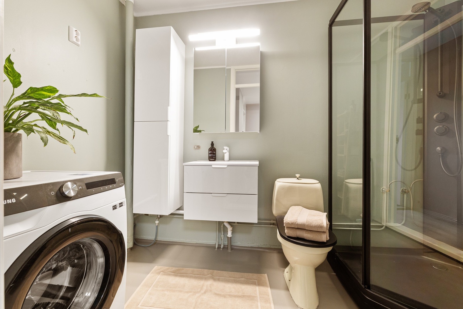 Badet er av god størrelse med vegghengt servantinnredning, speilskap med overlys, vegghengt baderomsmøbel og opplegg for vaskemaskin. Galleribilde