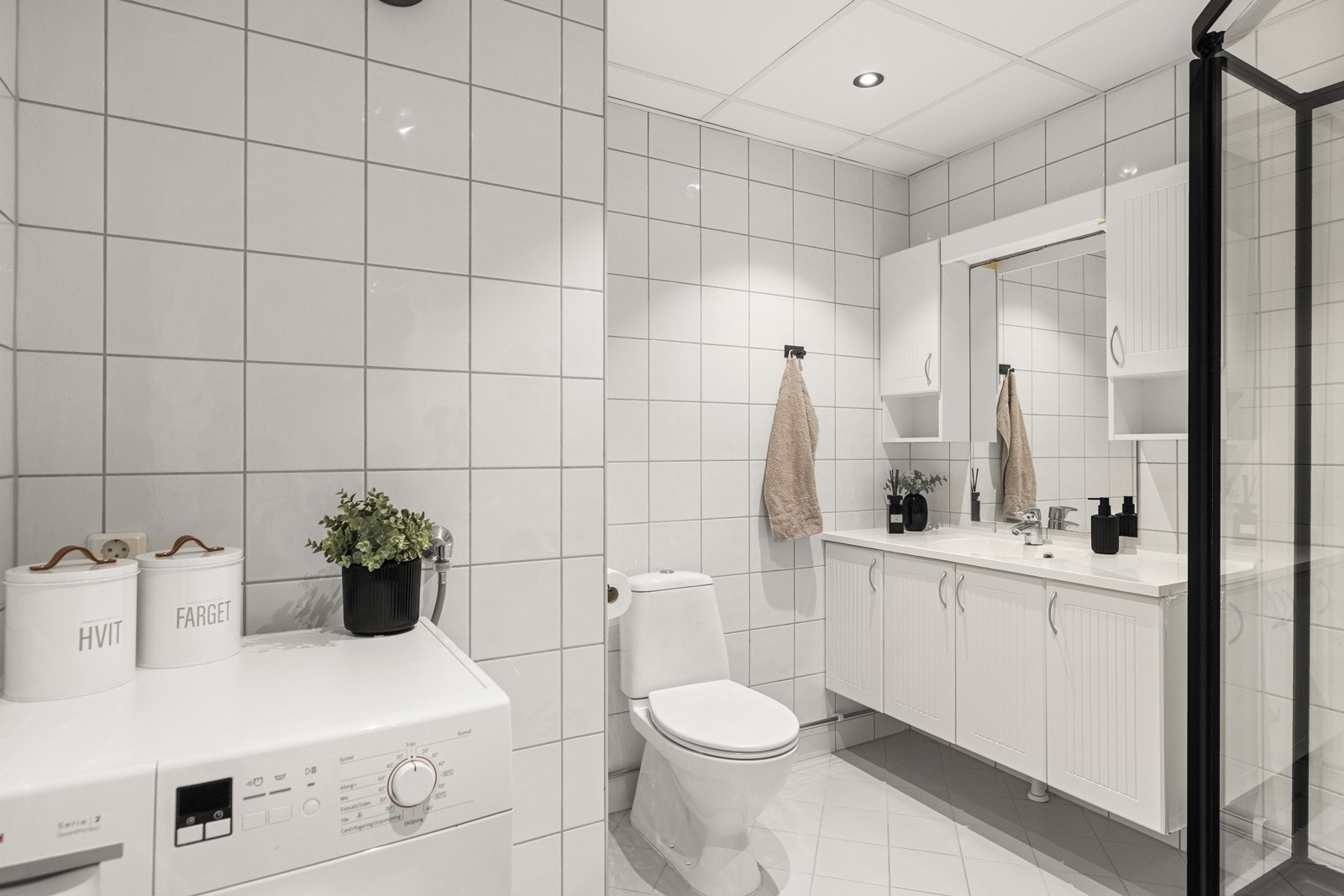 Flislagt bad med opplegg for vaskemaskin, servantinnredning og mekanisk avtrekk. Galleribilde