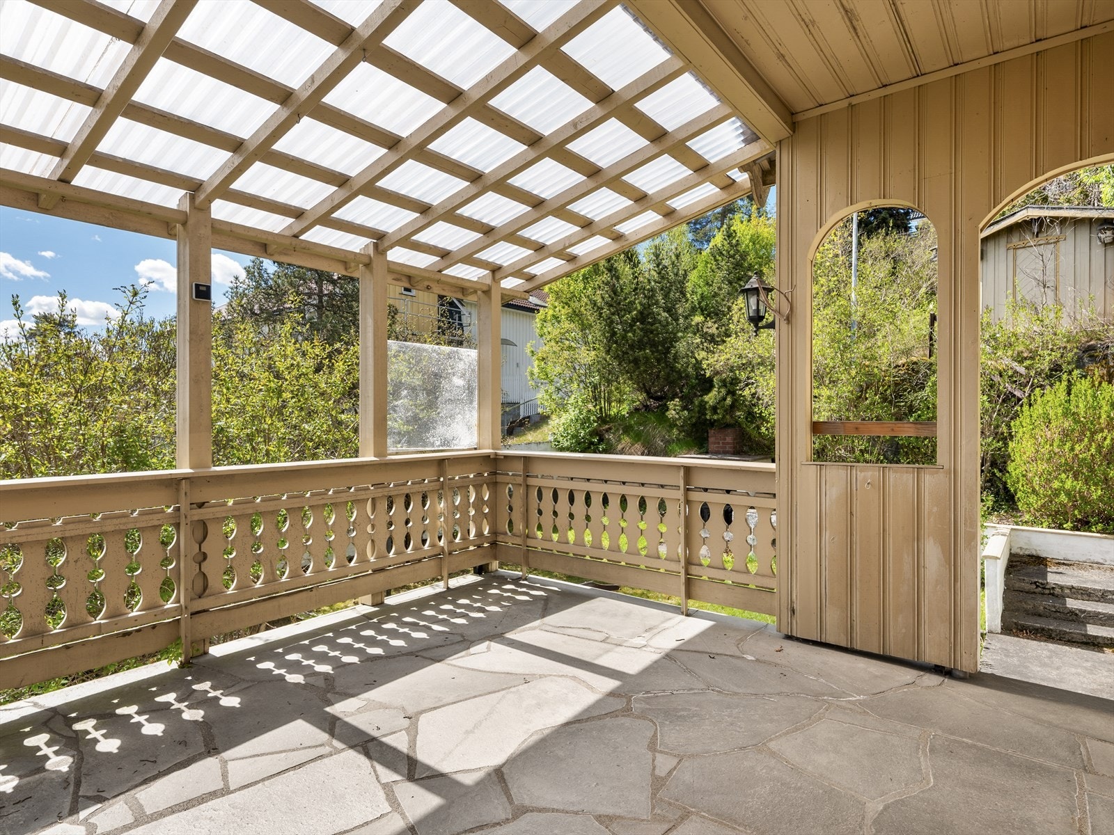 Verandaen har et solid rekkverk i tre og et delvis transparent tak som skjermer fra vær og vind. Galleribilde