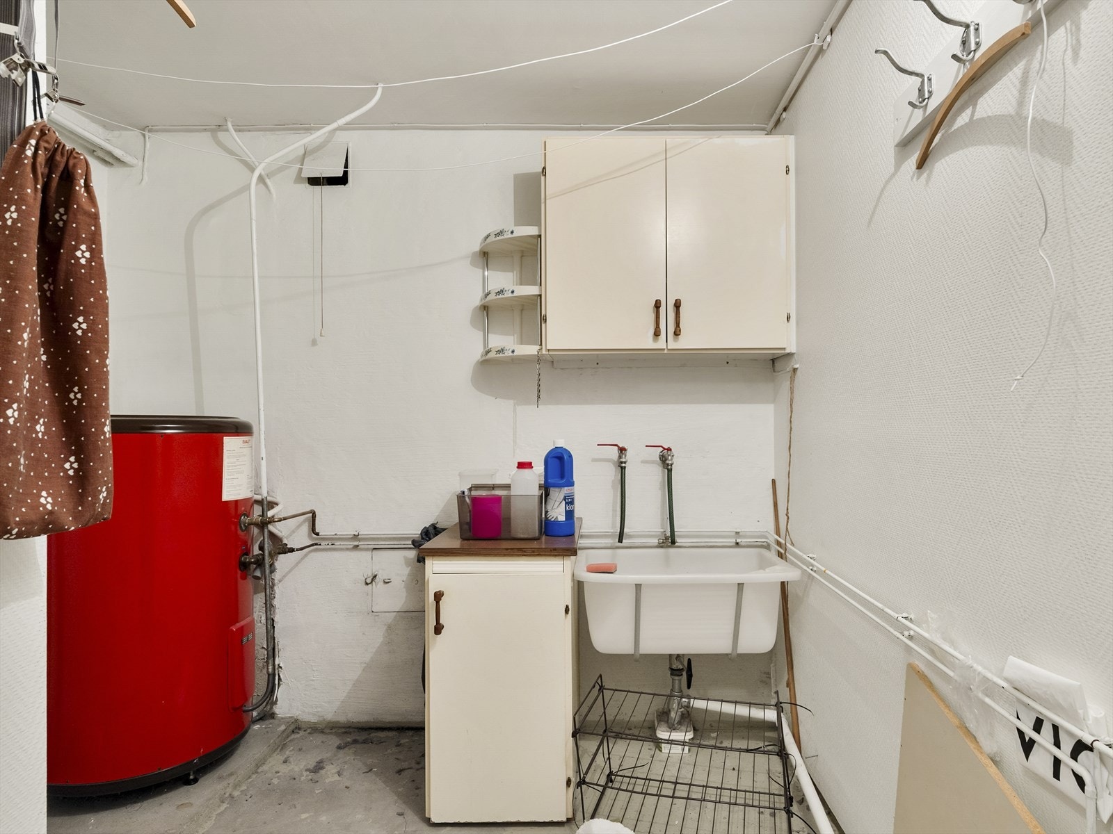 Vaskerommet i underetasjen har ubehandlet betonggulv, vaskekar og opplegg for vaskemaskin. Galleribilde
