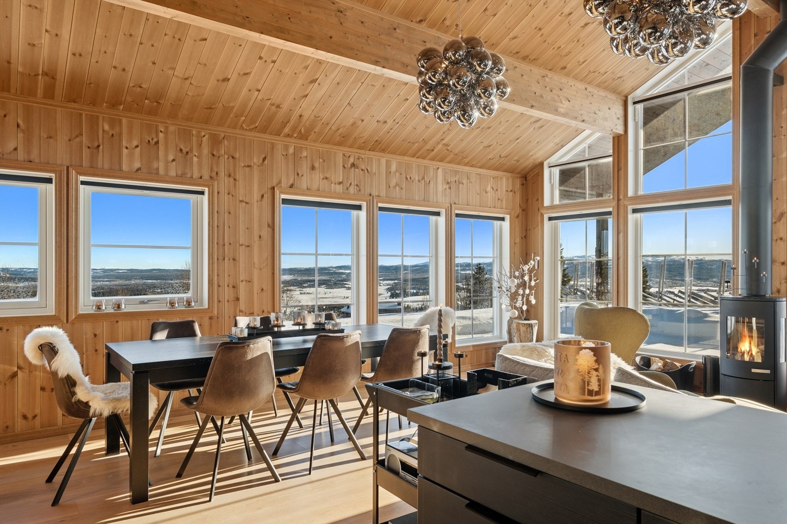 Vidstrakt panoramautsikt fra stue/spisestuen med peisovn og utgang solrik terrasse. Galleribilde