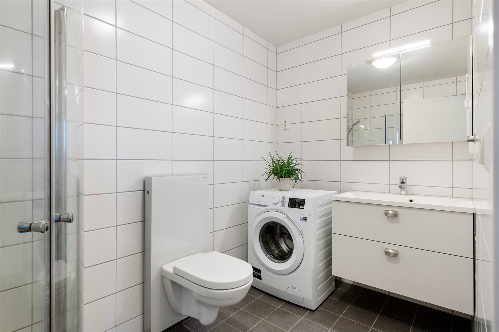 Stilrent bad med flislagte vegger og gulv som gir et helhetlig og solid uttrykk. Galleribilde