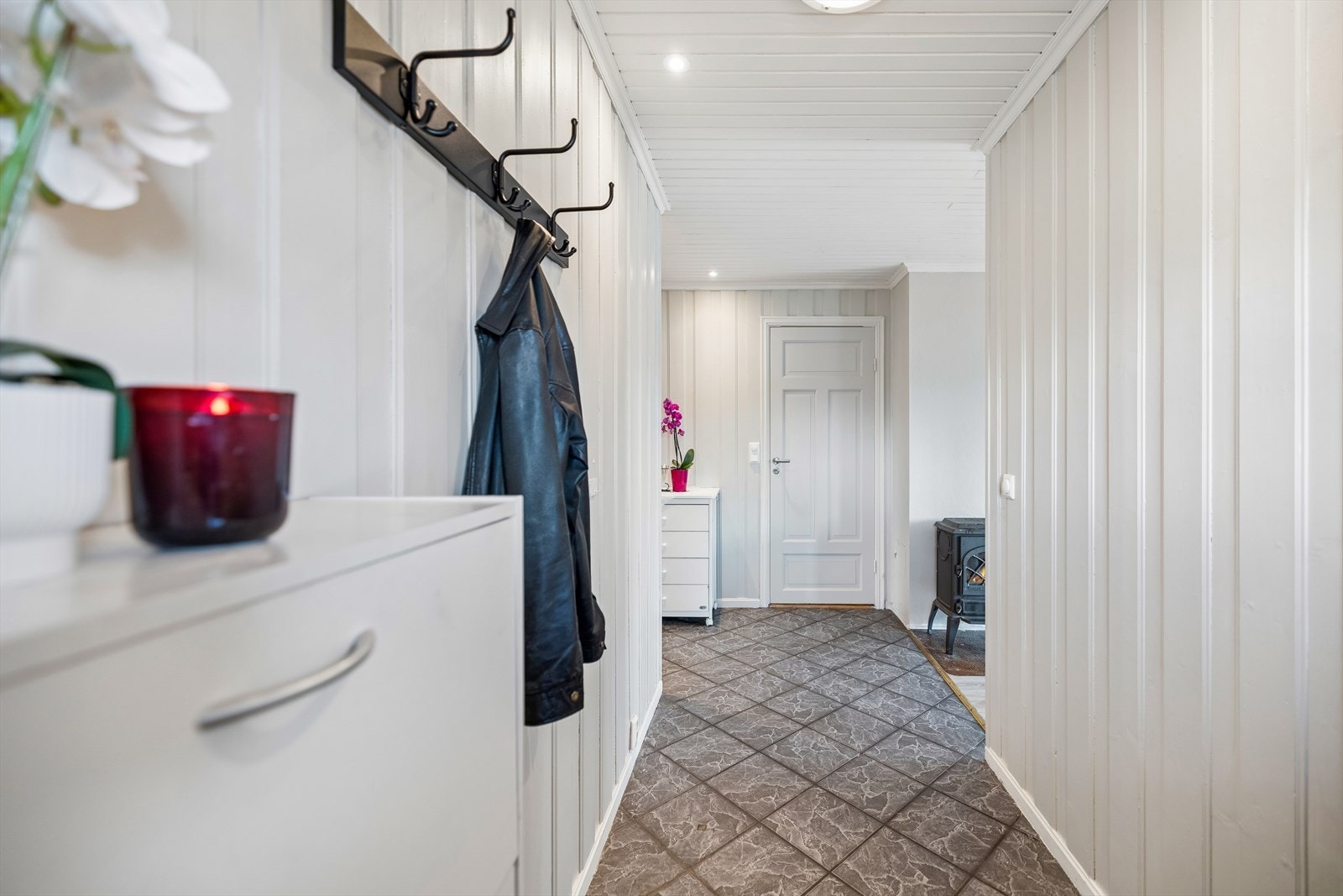 Entréen har flislagt gulv og vegger med trepanel. Herfra er det adkomst til leilighetens bad og oppholdsrom. Galleribilde