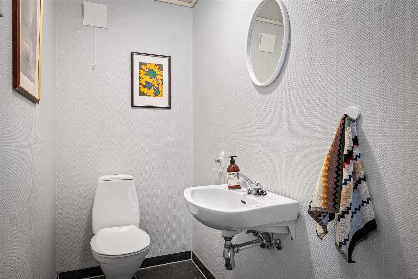 Toalettrom i kjeller med fliser på gulv, toalett og vask. Galleribilde