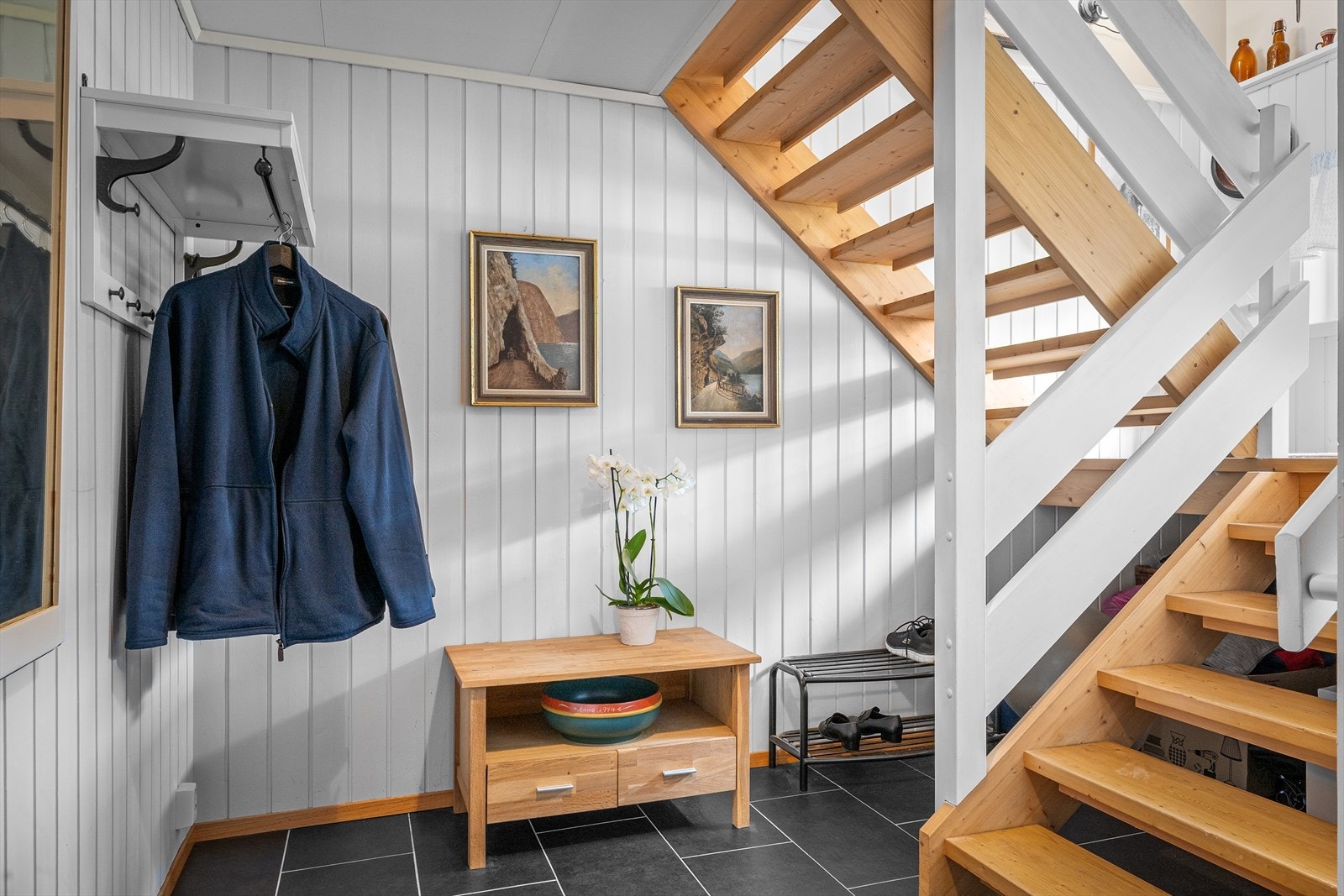 Gang i kjeller med åpen trapp opp til hovedetasjen. Galleribilde