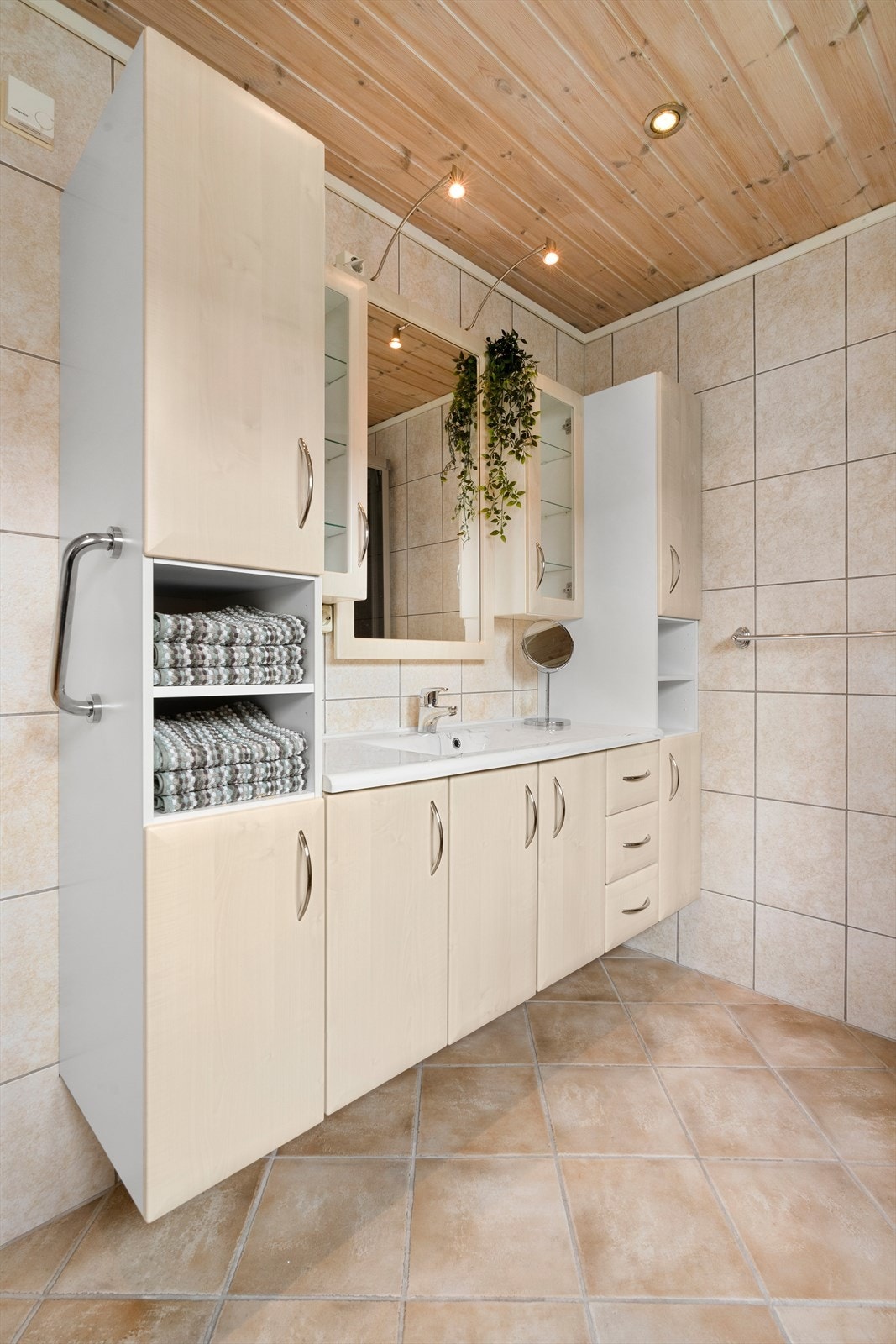 Badet har praktisk innredning med profilerte fronter og speil med belysning. Galleribilde