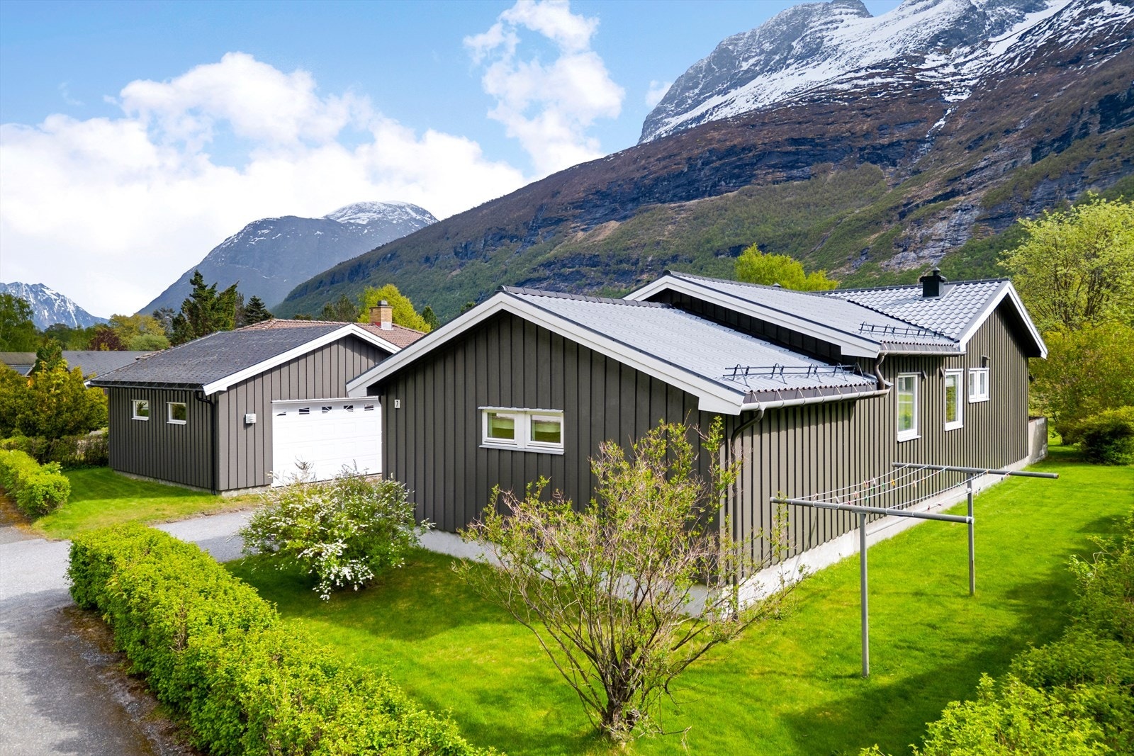 Eiendommen har en opparbeidet tomt med plen, beplantning og veranda av treverk. Galleribilde