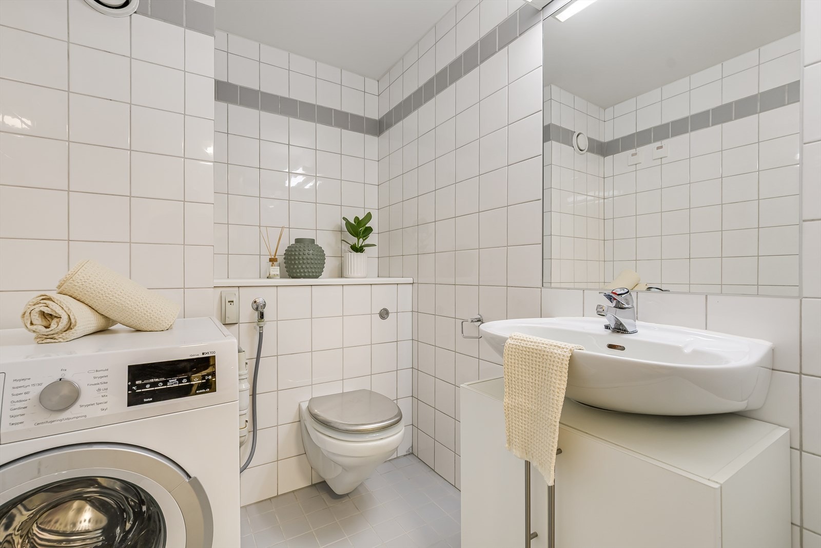 Badet/toalettrom har opplegg for vaskemaskin, servant med innredning, vegghengt klosett og vannbåren varme i gulv. Galleribilde