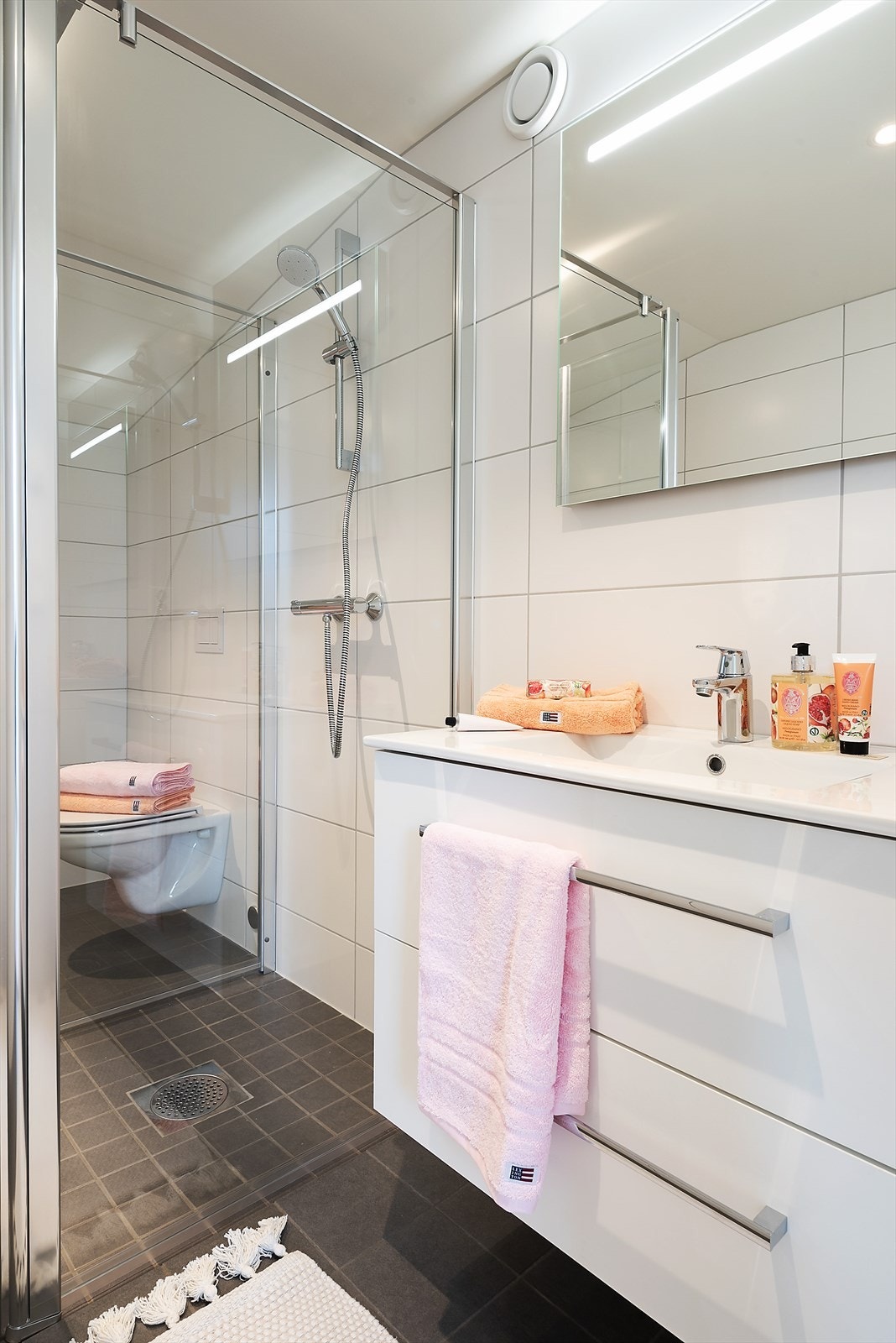 Badet er utstyrt med dusjhjørne, vegghengt toalett og en moderne baderomsinnredning. Galleribilde