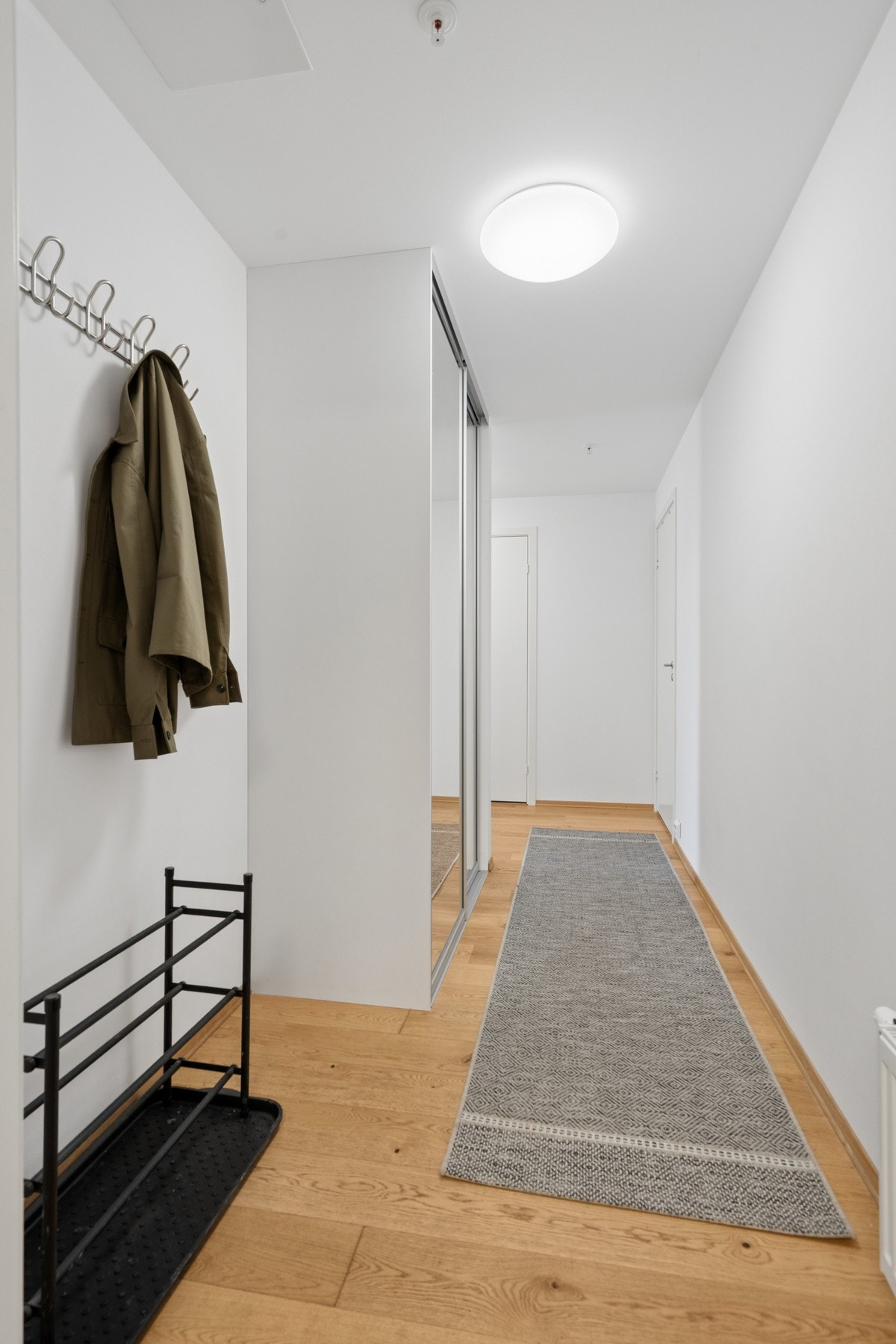 Praktisk entré med parkett på gulv og skyvedørsgarderobe for oppbevaring av yttertøy. Galleribilde