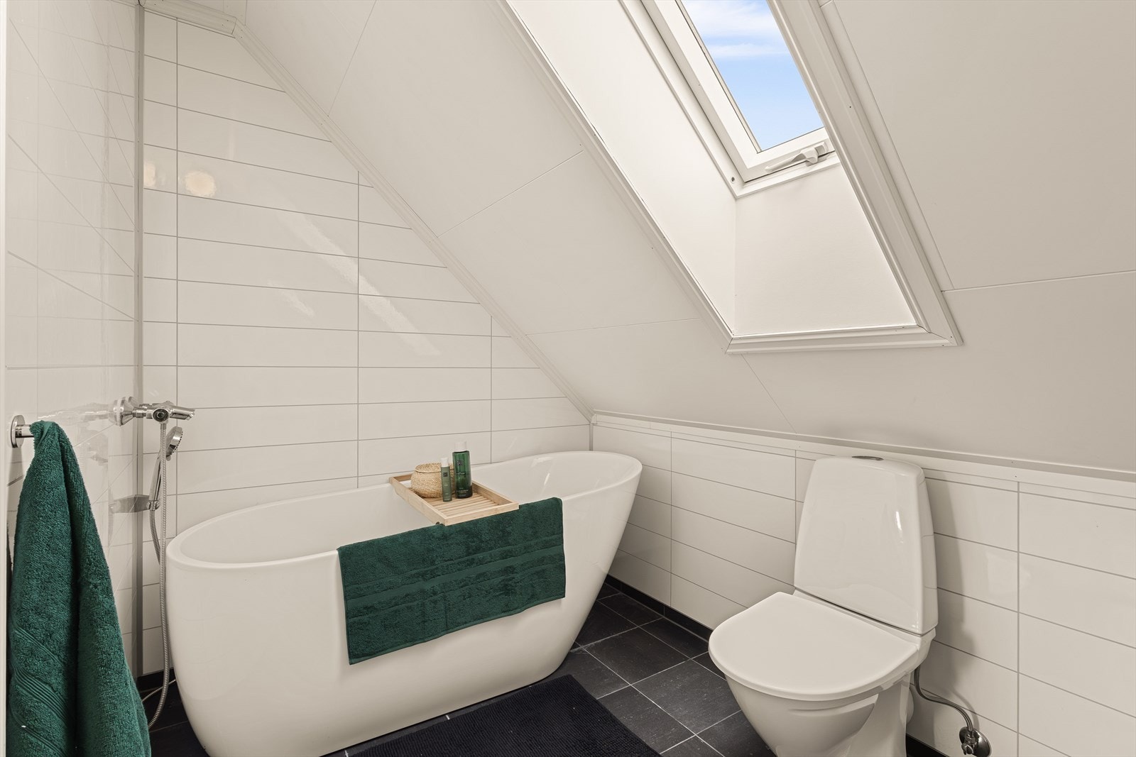 Badet er innredet med servant i baderomsmøbel, toalett, og badekar. Galleribilde