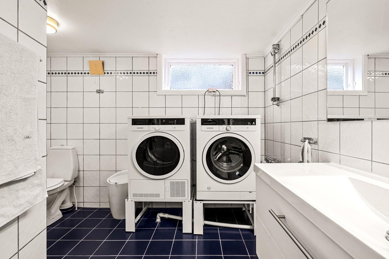 Rommet er innredet med dusj, gulvstående wc, servantskap, speil og opplegg for vaskemaskin. Galleribilde