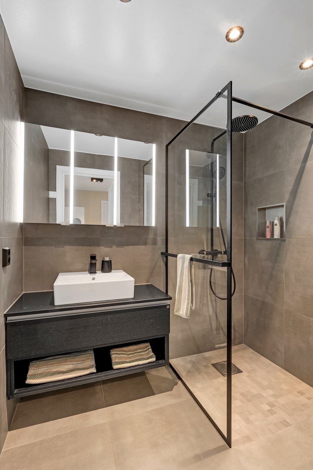 Badet har flislagte gulv og vegger, elektriske varmekabler og veggmontert servant. Galleribilde