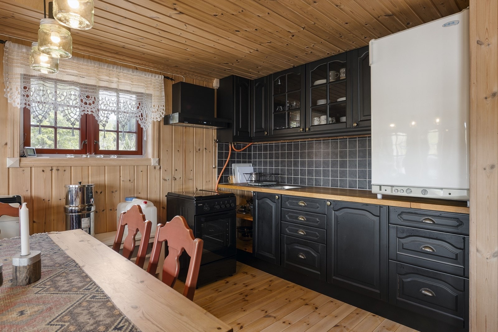 Pent kjøkken med hyttepreg, gassdrevet komfyr og kjøleskap. Galleribilde
