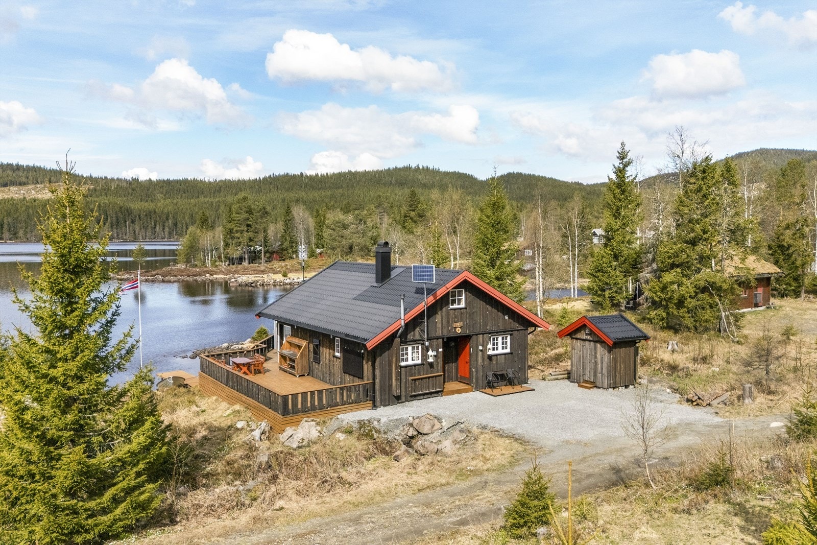 Gruset gårdsplass med plass til flere biler og frittstående utebod. Galleribilde