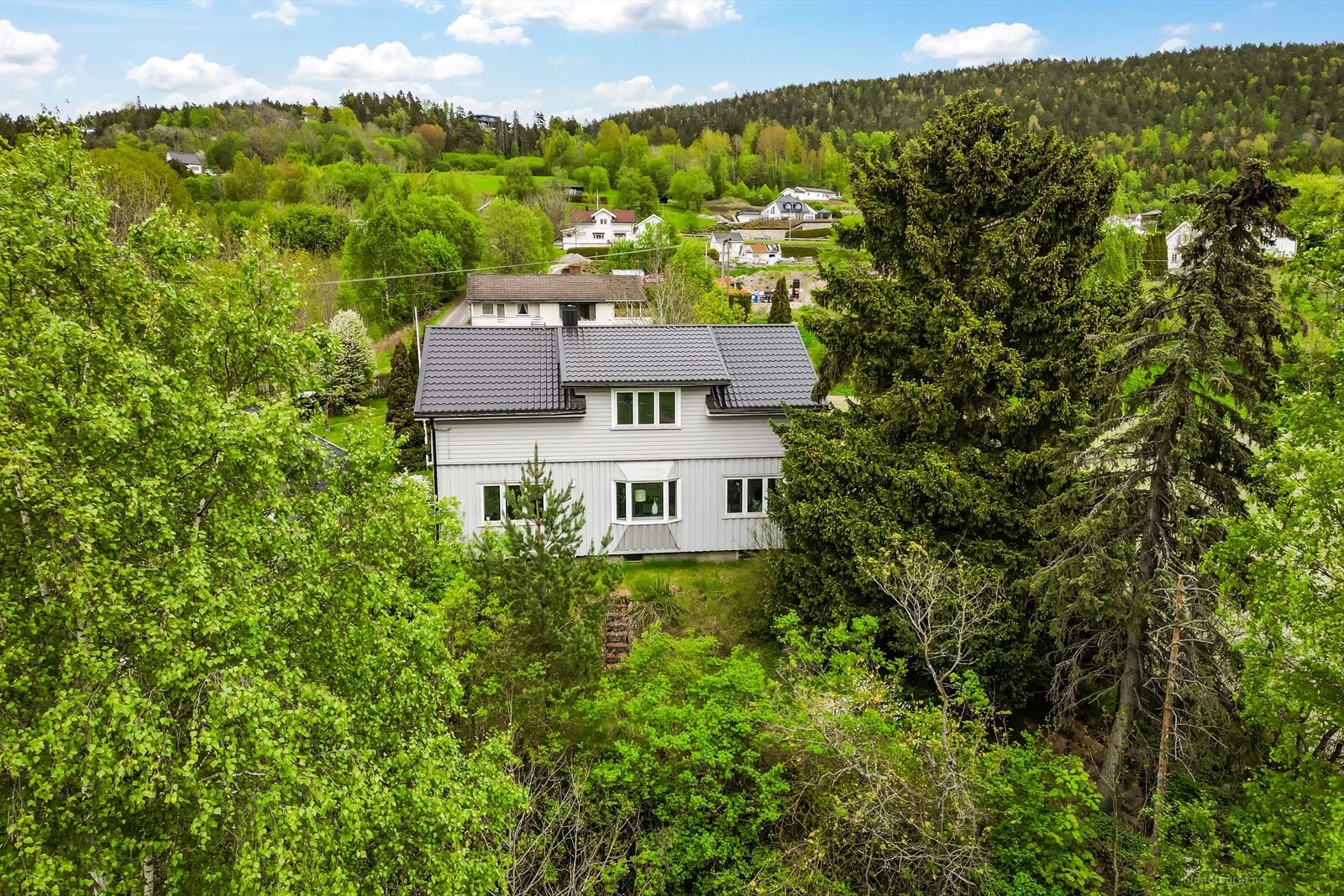 Eiendommen er omkranset av en stor hage med gressplen og etablert beplantning. Galleribilde