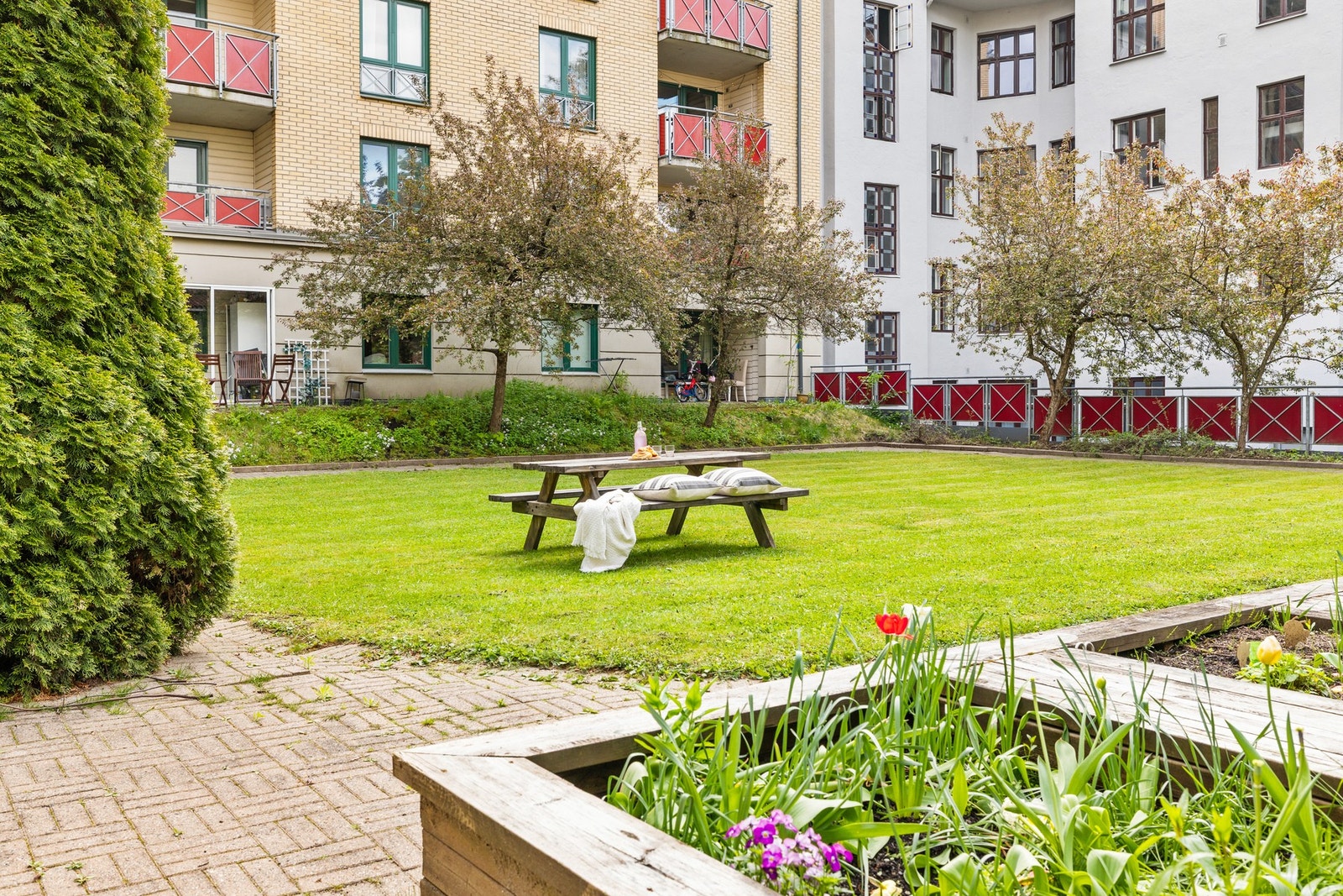 Bakgården består av gressplen, brosteinlagte internveier, sittegrupper, hyggelig beplanting og prydbusker Galleribilde