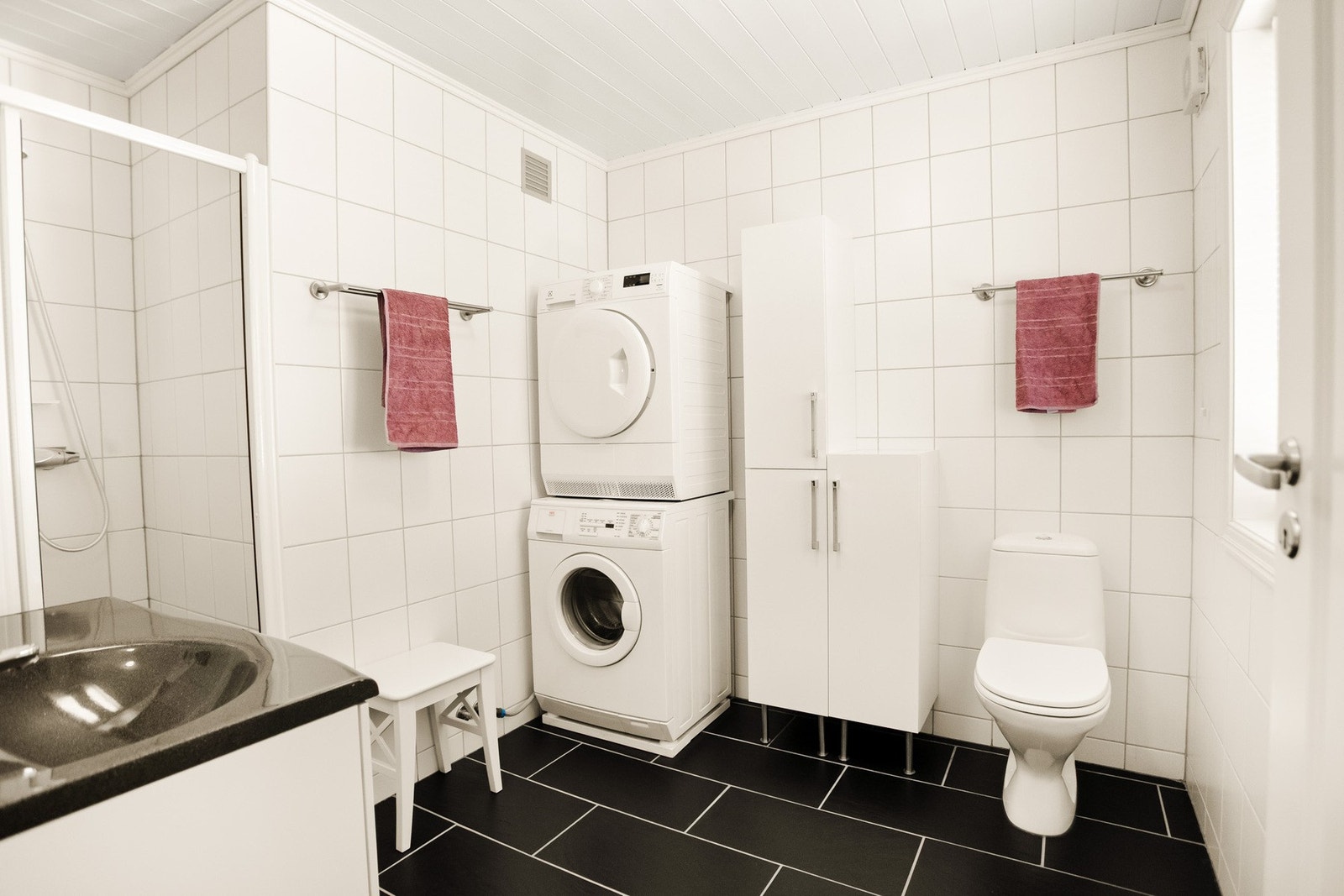 Bad med flislagt gulv med elektriske varmekabler og flislagte vegger, kombinert med panelkledd himling. Galleribilde