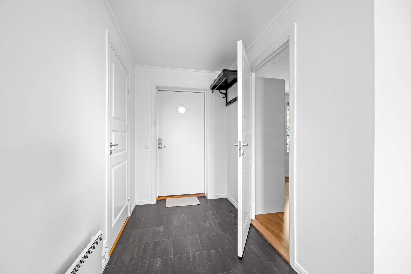 Du ønskes velkommen inn i en hvitmalt entré med grå fliser på gulv. Her er det god plass til garderobe eller kommode for lagring av diverse yttertøy. Galleribilde