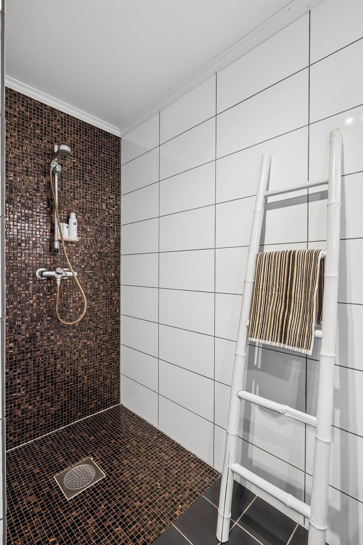 Badet er utstyrt med veggmontert toalett, dusjhjørne og innredning med nedfelt servant. Galleribilde