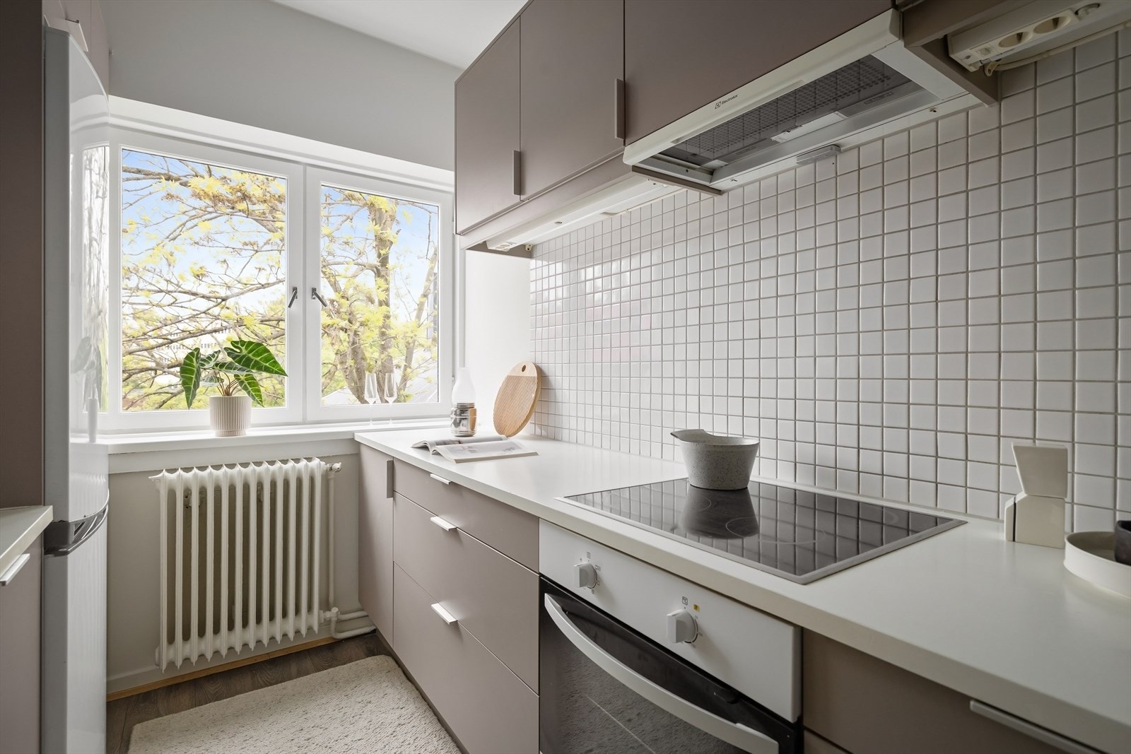 Kjøkkenventilator med kullfilter og fliser over laminert benkeplate. Galleribilde