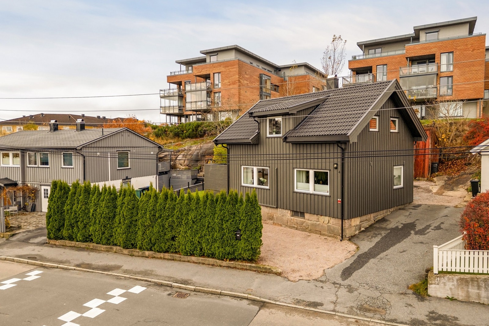 En innbydende eiendom med frodig hekk, lun uteplass og praktiske parkeringsplasser rett utenfor døren. Galleribilde