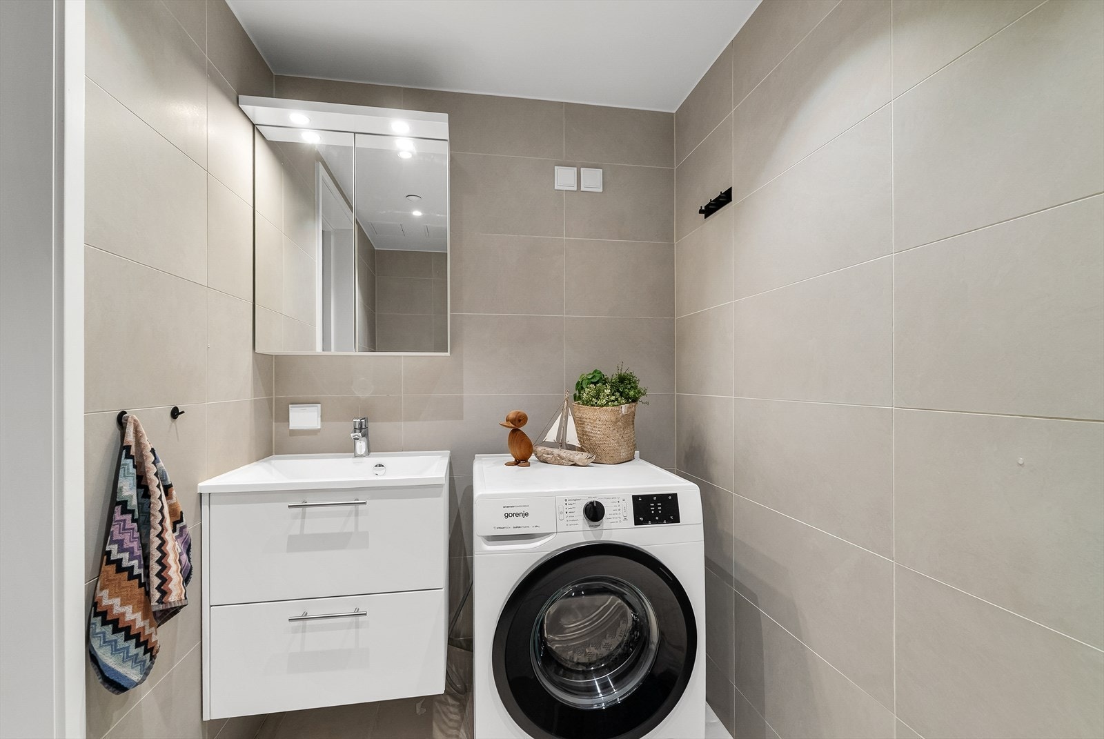 Badet har flislagt gulv med vannbåren gulvvarme, fliser på veggene og malt himling Galleribilde