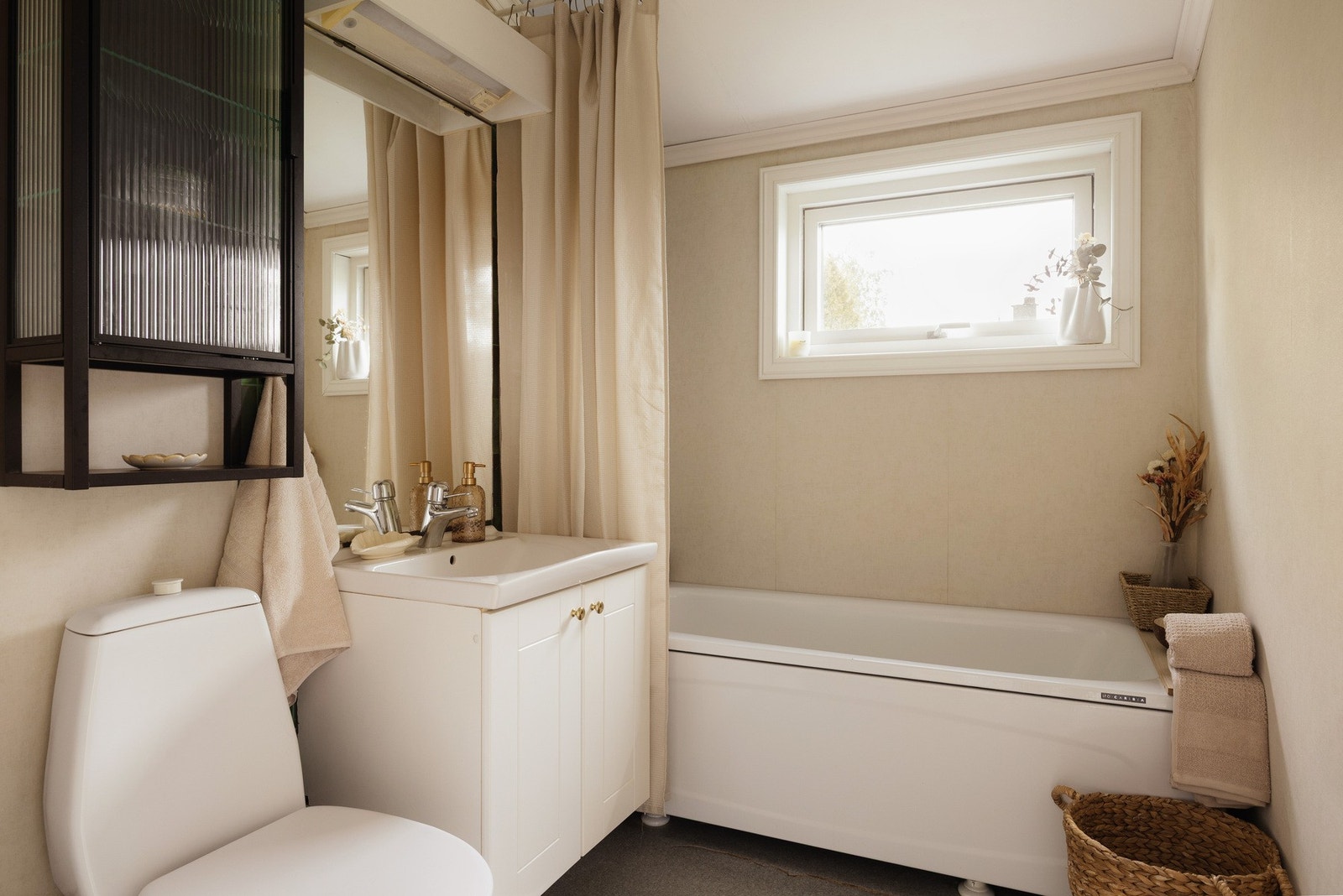 Badet er innredet med grått gulvbelegg og lys våtromstapet på veggene, som gir rommet et lyst og praktisk uttrykk. Galleribilde