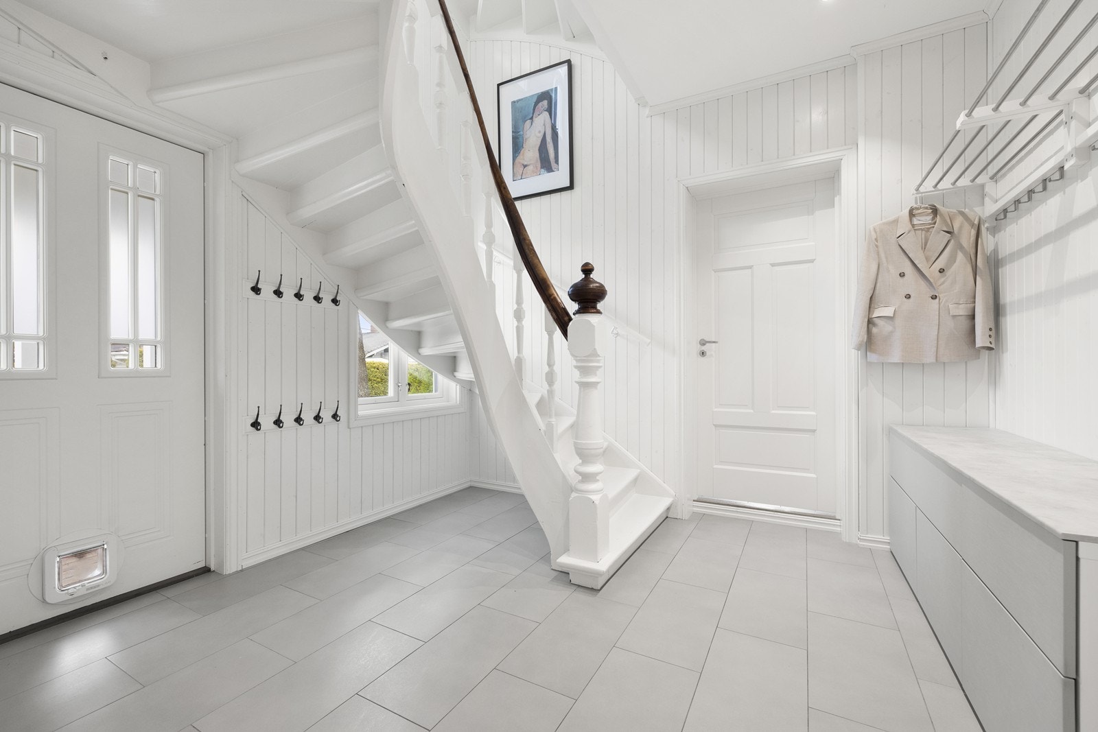 Romslig hall med god plass til yttertøy og sko. Herfra går den flotte tretrappen til de øvrige etasjene. Galleribilde