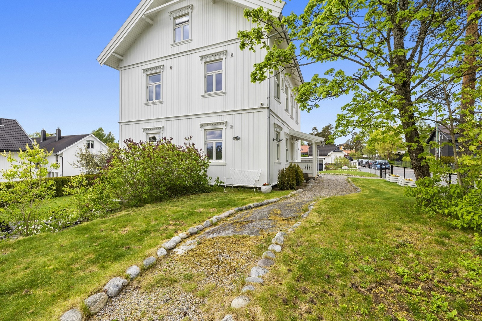 Gangsti langs husveggen leder til hagen på baksiden. Galleribilde