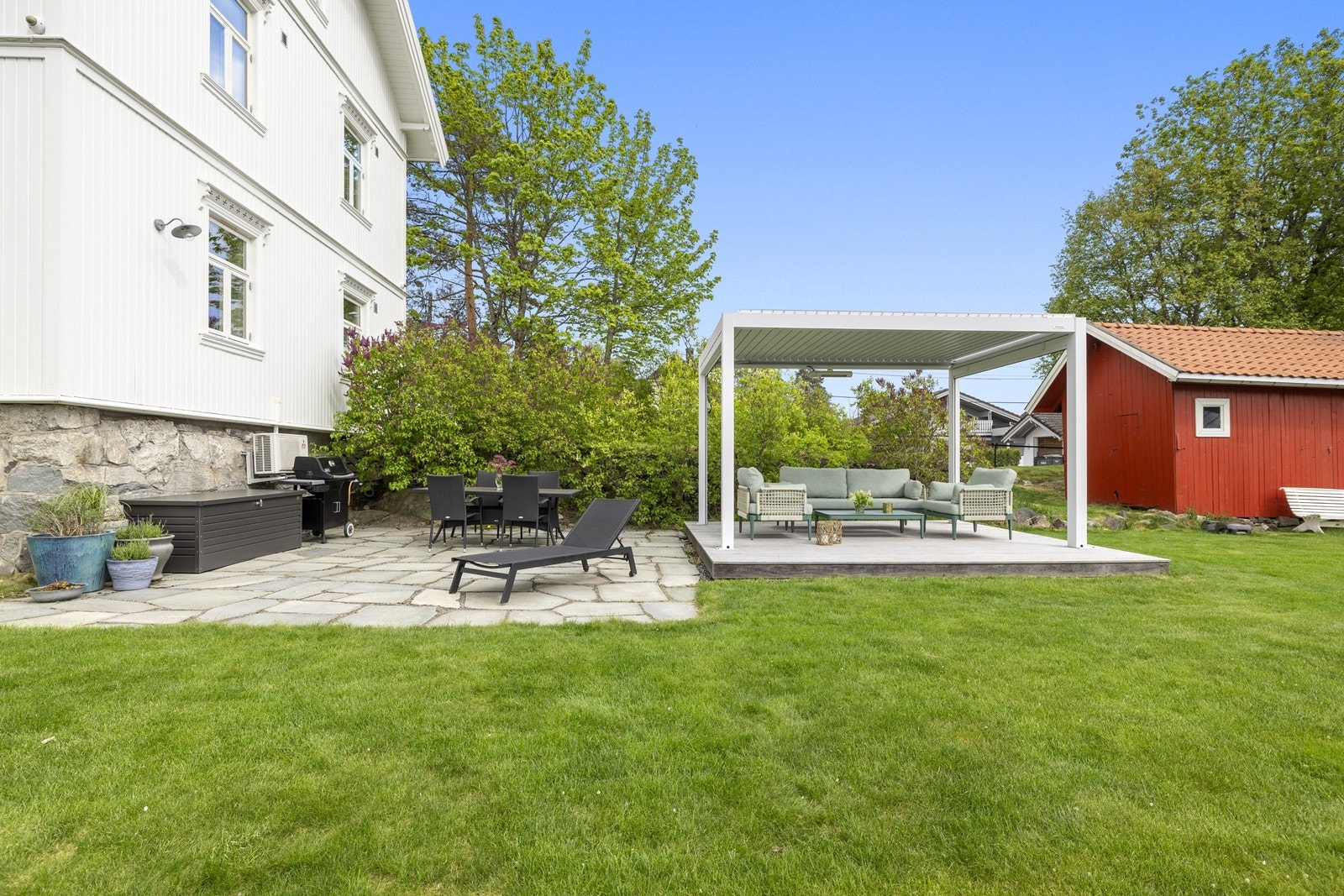 Flere uteplasser i hagen, inkludert en steinsatt platting og en pergola. Galleribilde