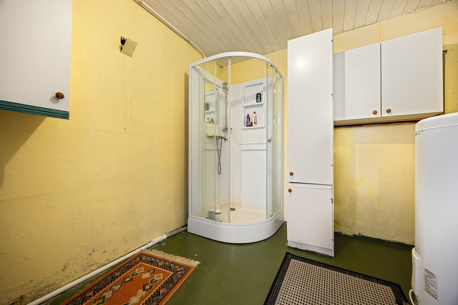 Bad/vaskerommet er innredet med dusjkabinett, servantmøbler, varmtvannstank og opplegg for vaskemaskin. Galleribilde